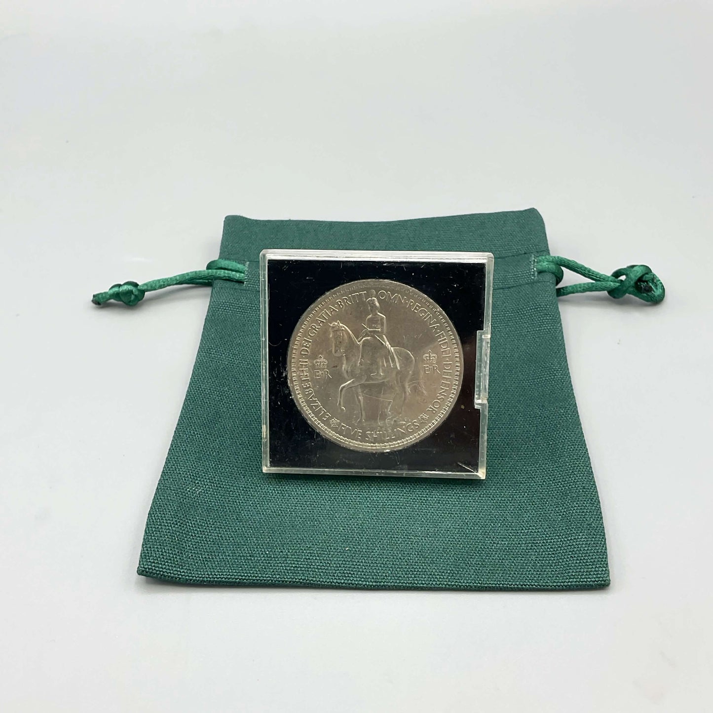 Reverse side of Queen Elizabeth II Coronation Five Shilling Coin in a Perspex Case on a green gift bag