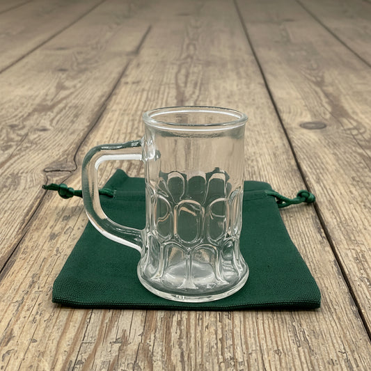 miniature glass tankard on a green bag on an old wood table