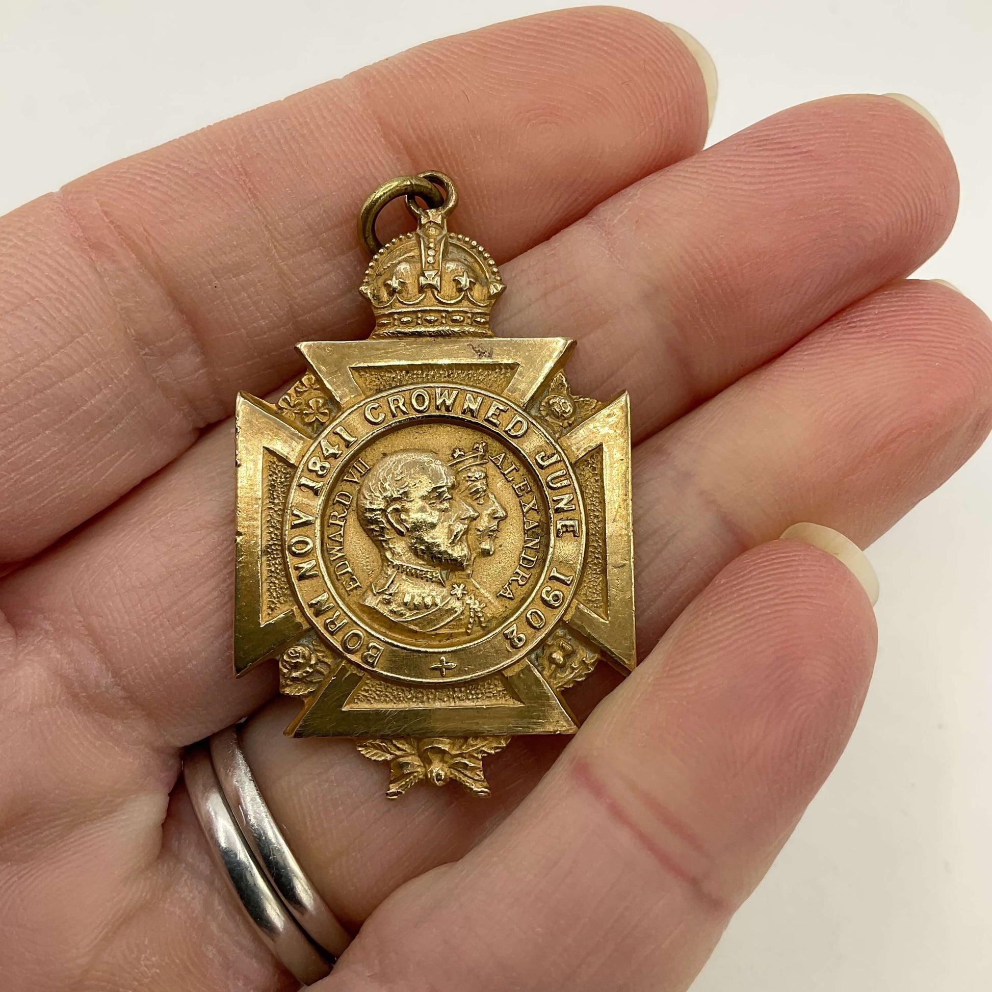 Brass 1902 coronation medal in a hand