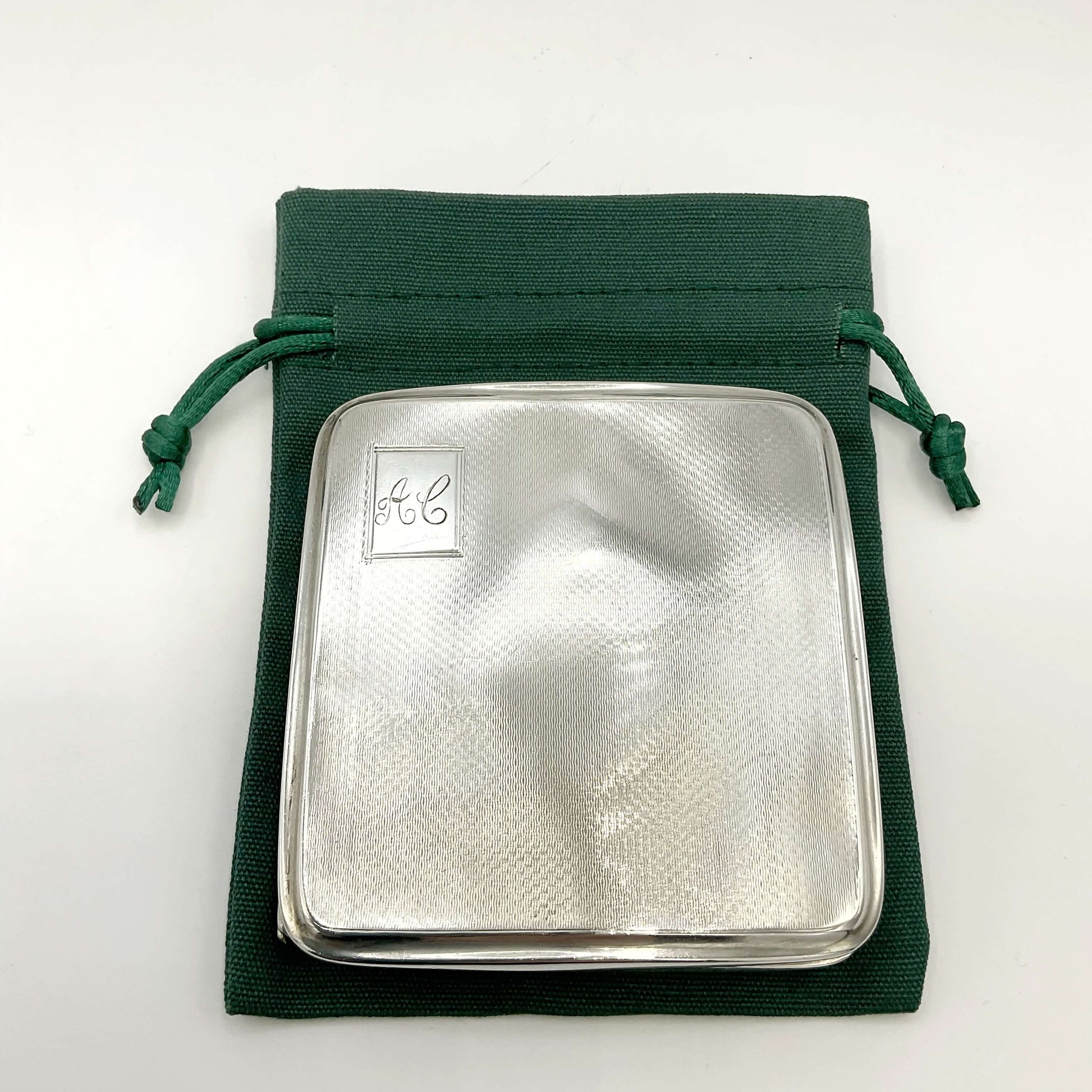 Silver cigarette case on green bag