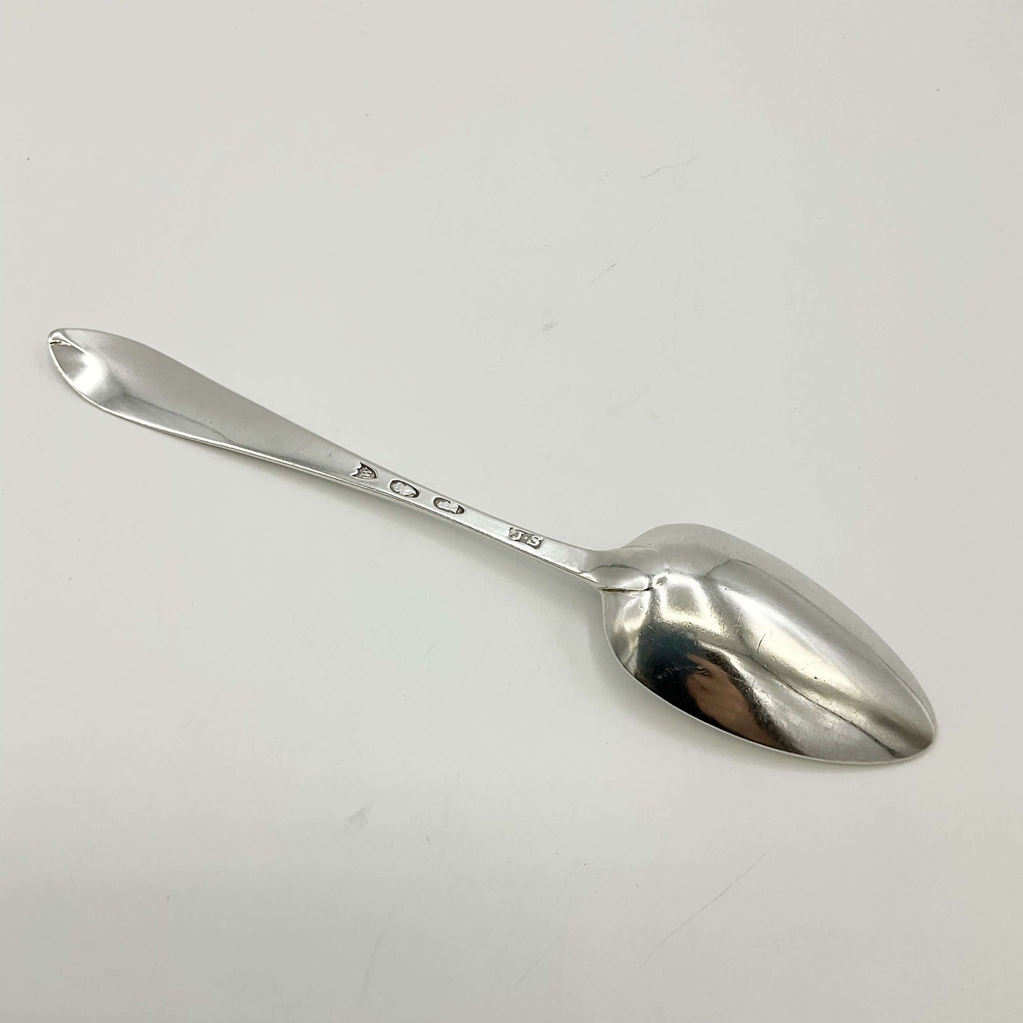 Back of Antique Silver Dessert Spoon on a white background 