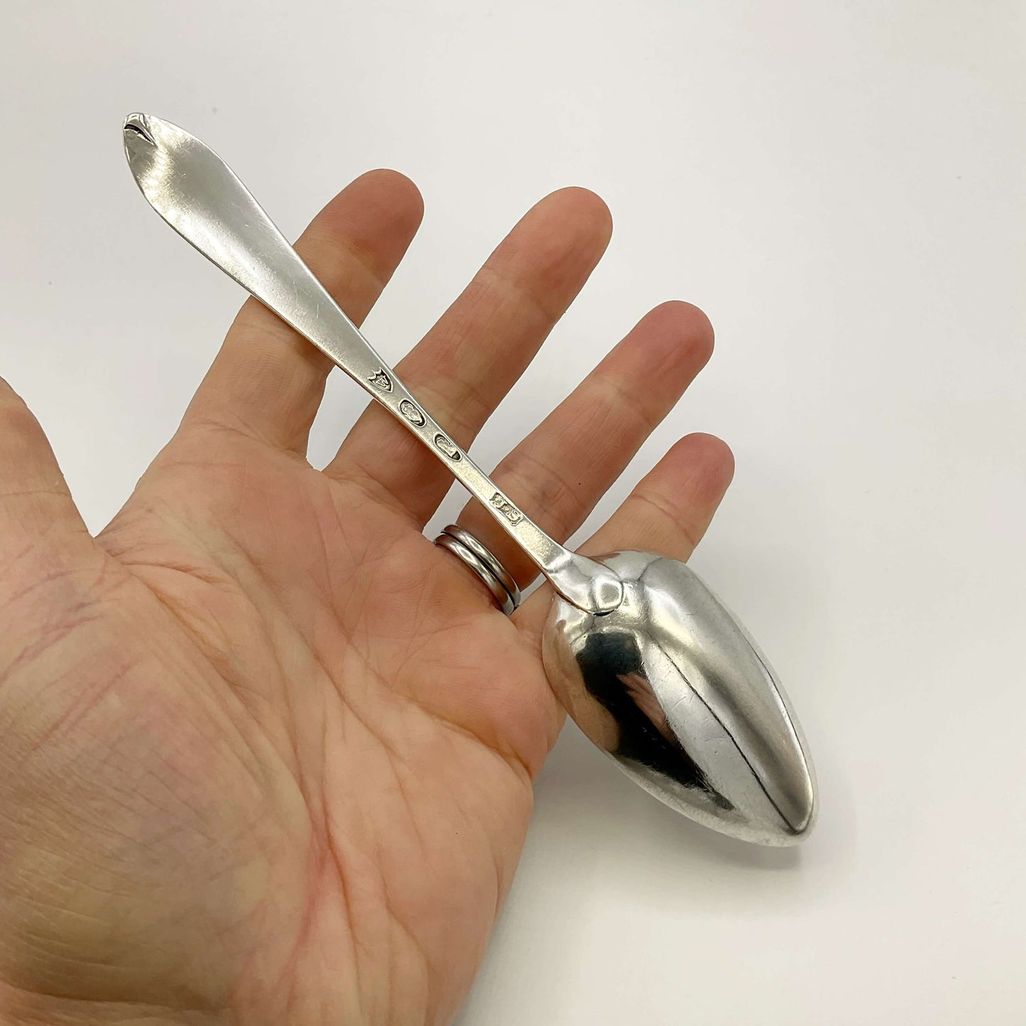 Back of Antique Silver Dessert Spoon held in a hand