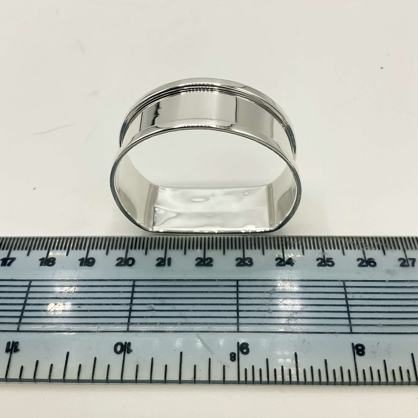 Vintage silver napkin ring on a white background next to a ruler showing the diameter as 4.5cm 