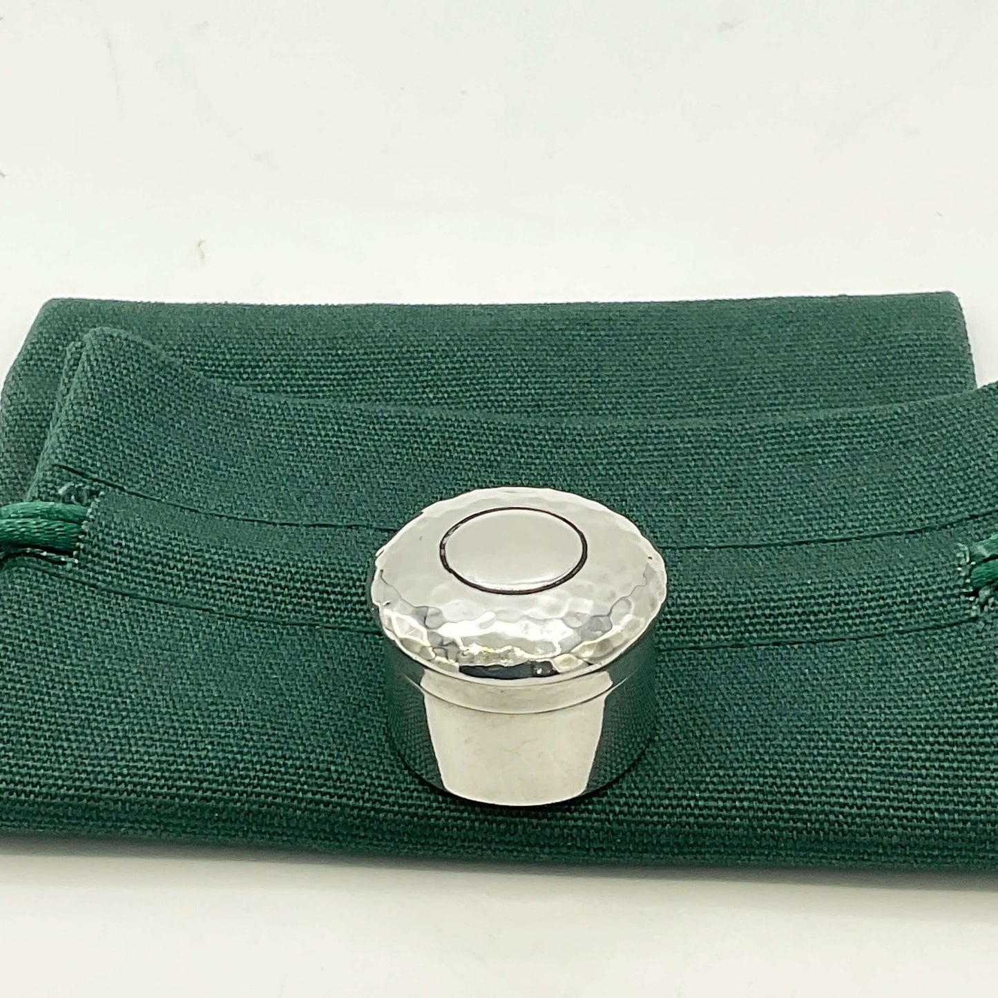 Antique silver pill box on a green gift bag