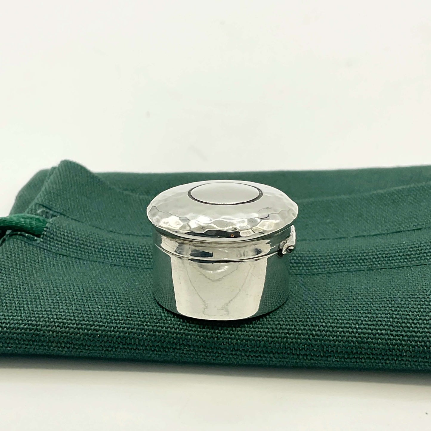 Side view of Antique silver pill box on a green gift bag