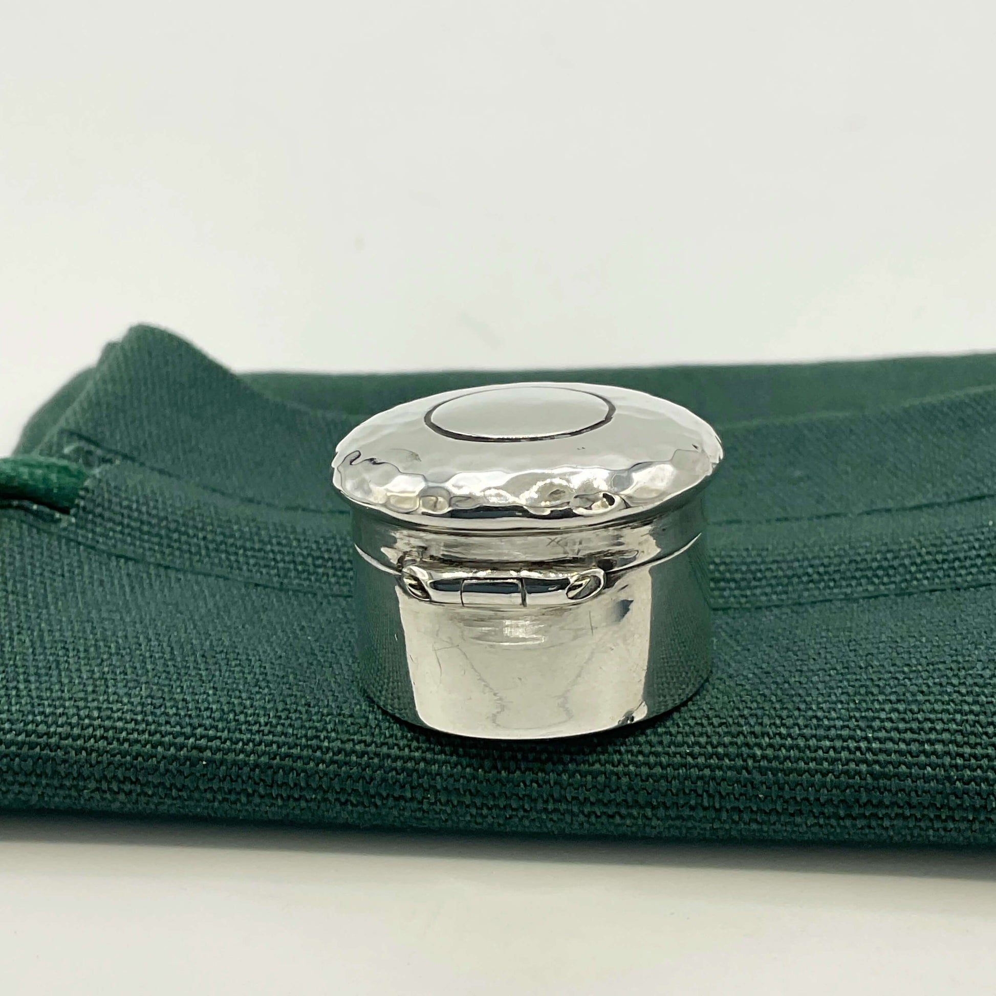 Back view of Antique silver pill box on a green gift bag