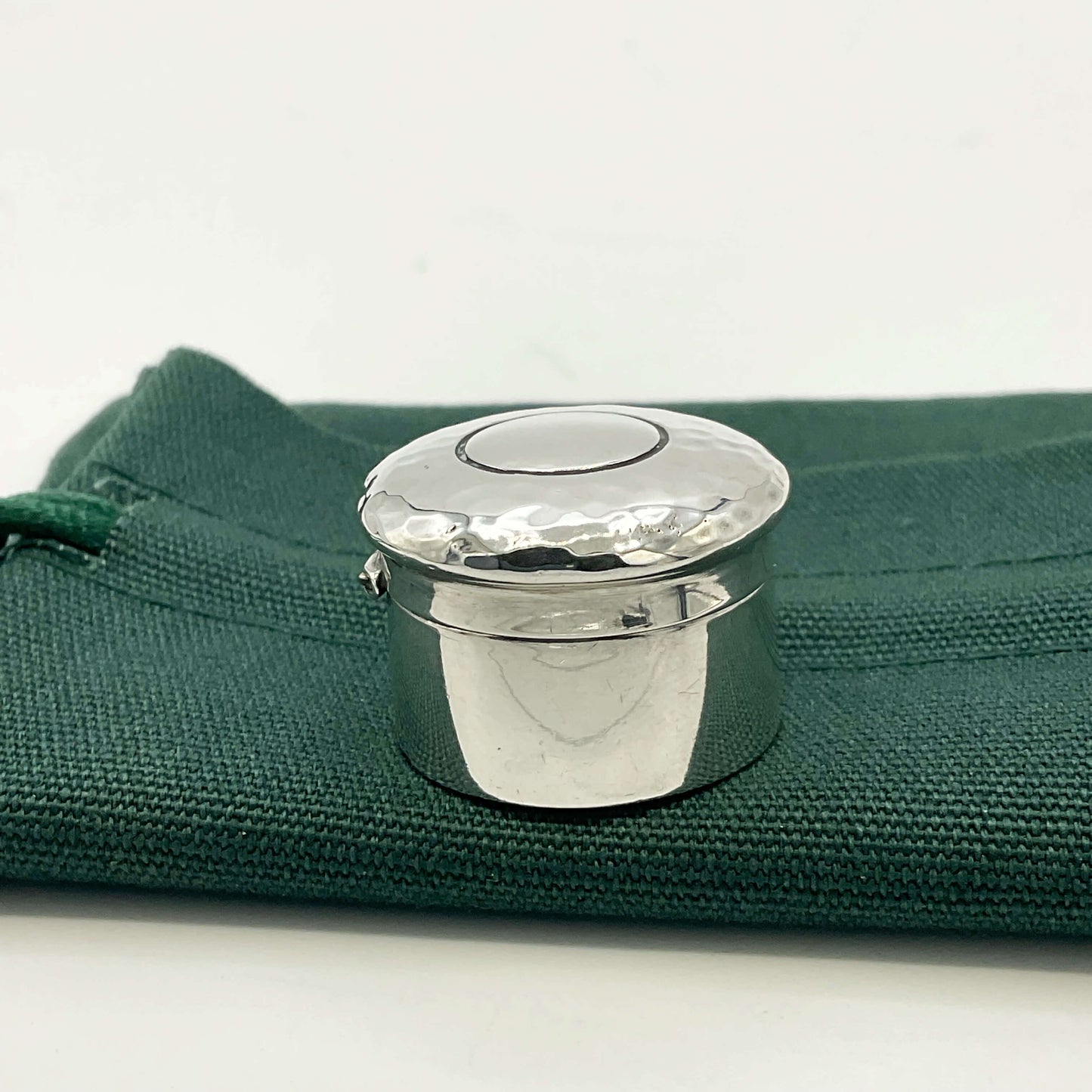 Side view of Antique silver pill box on a green gift bag