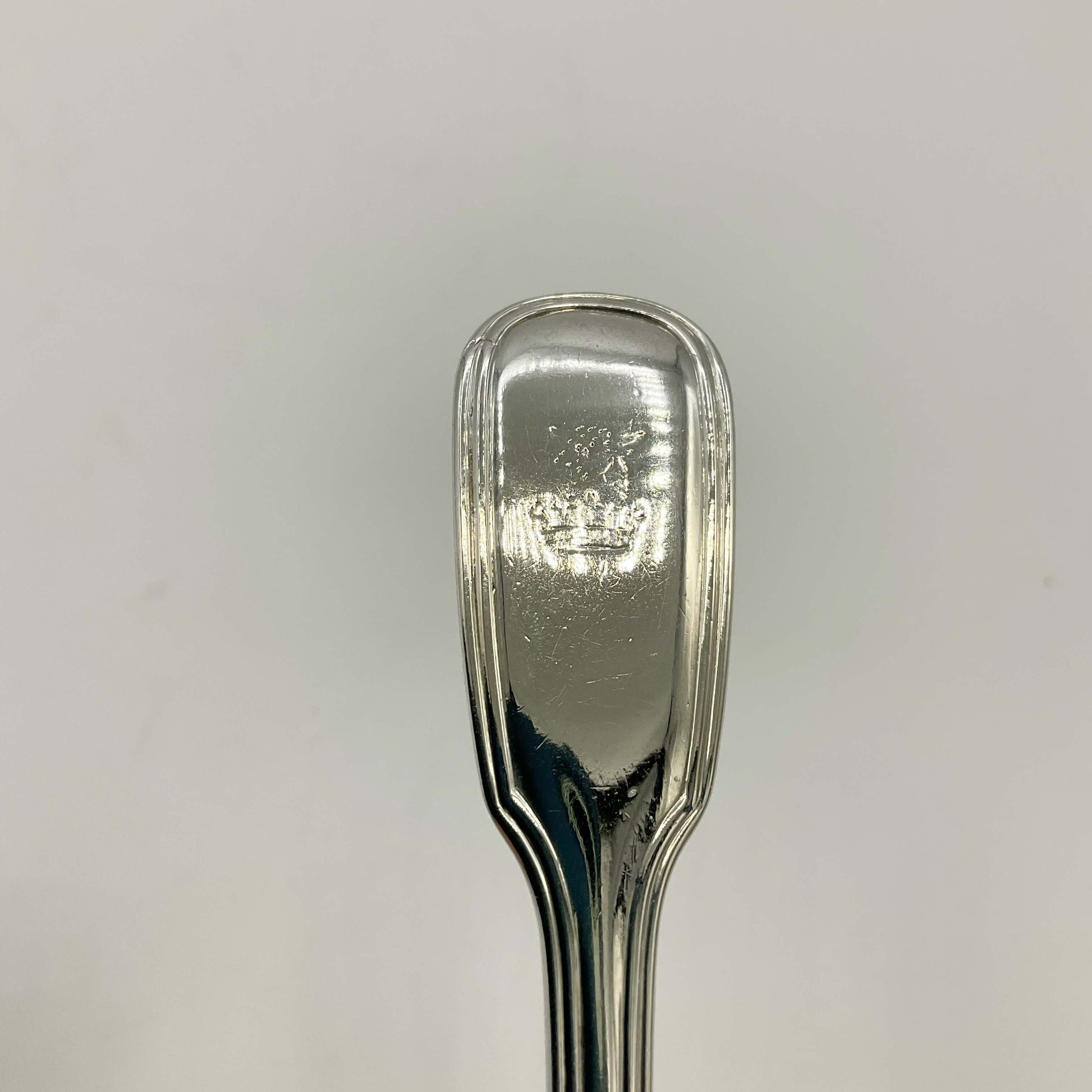 Top of Antique silver mustard spoon on a white background showing a bull and crown motif
