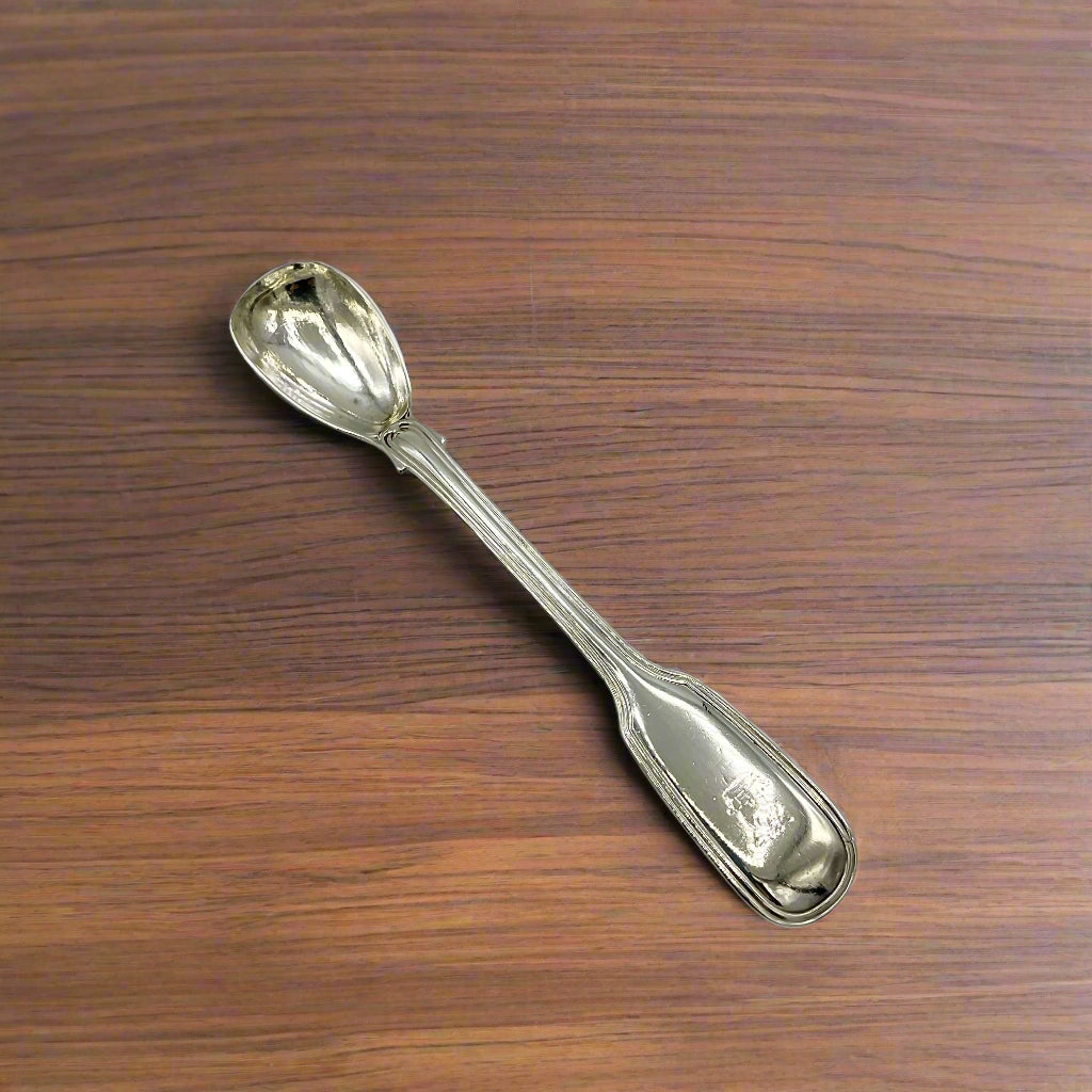 Antique silver mustard spoon on a wooden table