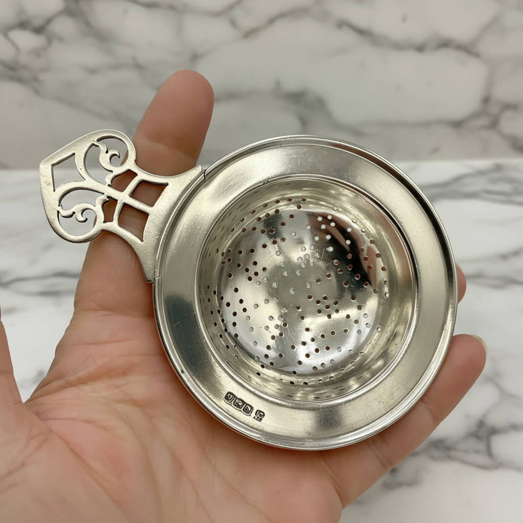 Antique 1925 sterling silver tea strainer with intricate design, crafted by Beeches Vintage, featuring detailed perforations and vintage charm.