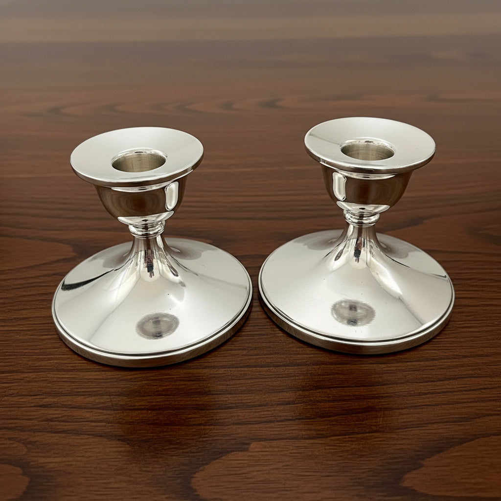 Two silver candle holders on a wooden surface