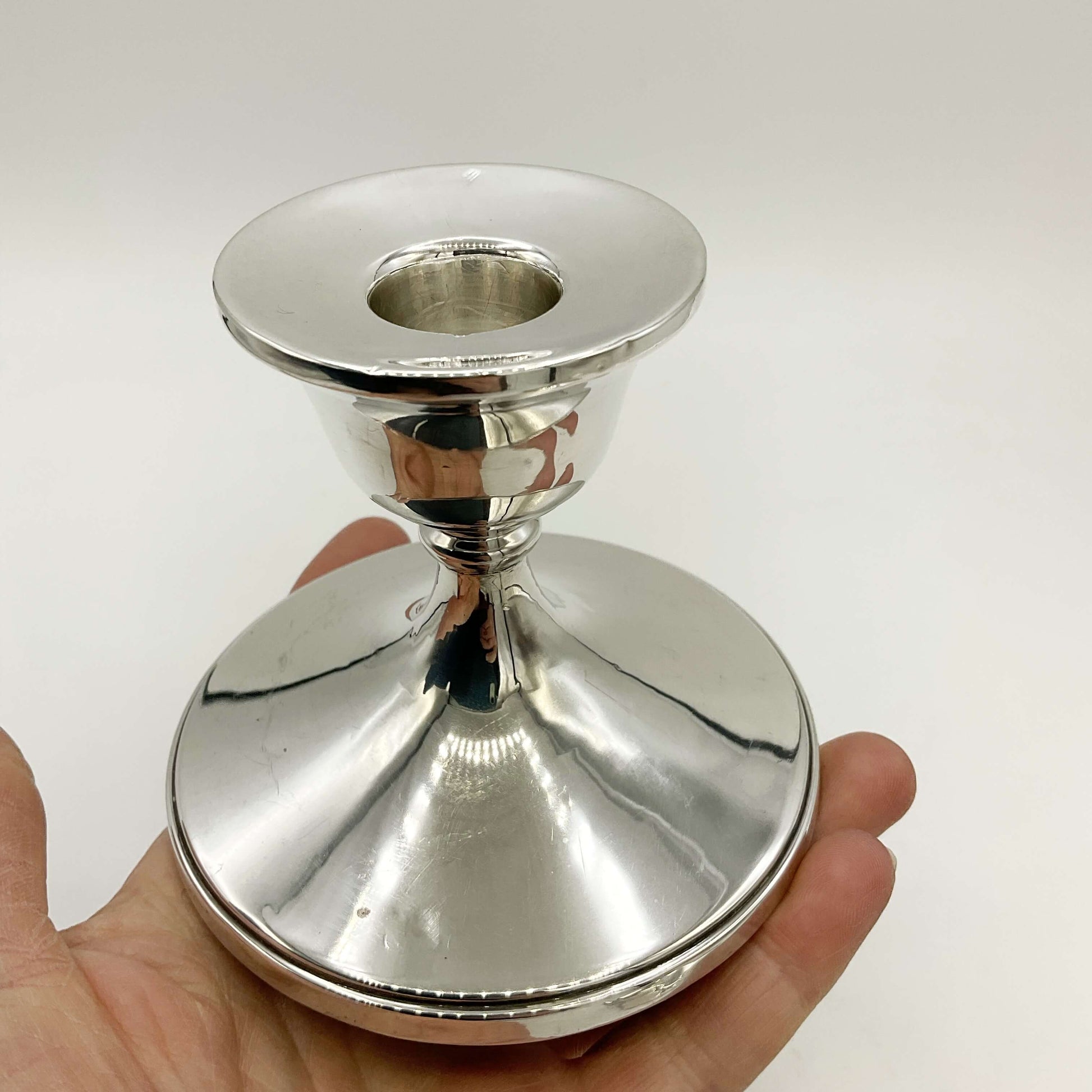 One silver candlestick holder held in a hand