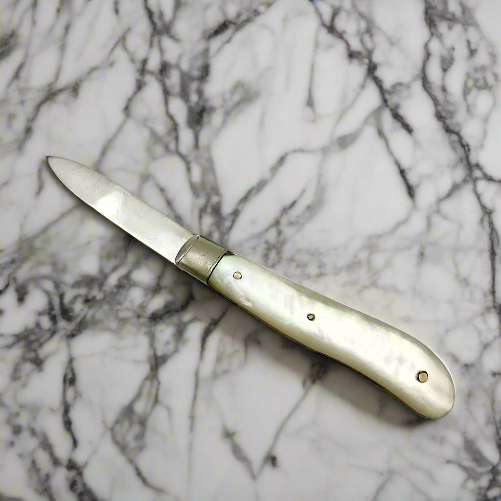 Other side of Silver bladed fruit knife with a mother of Pearl handle on a marble worktop