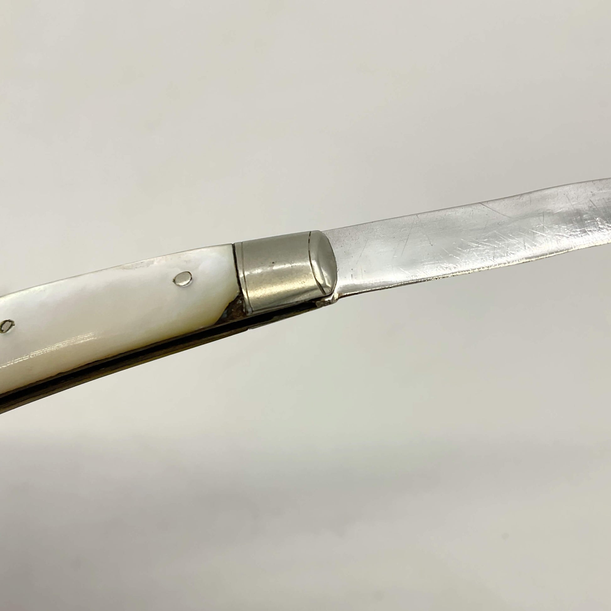 Silver bladed fruit knife with a mother of Pearl handle showing the two chips to the handle 