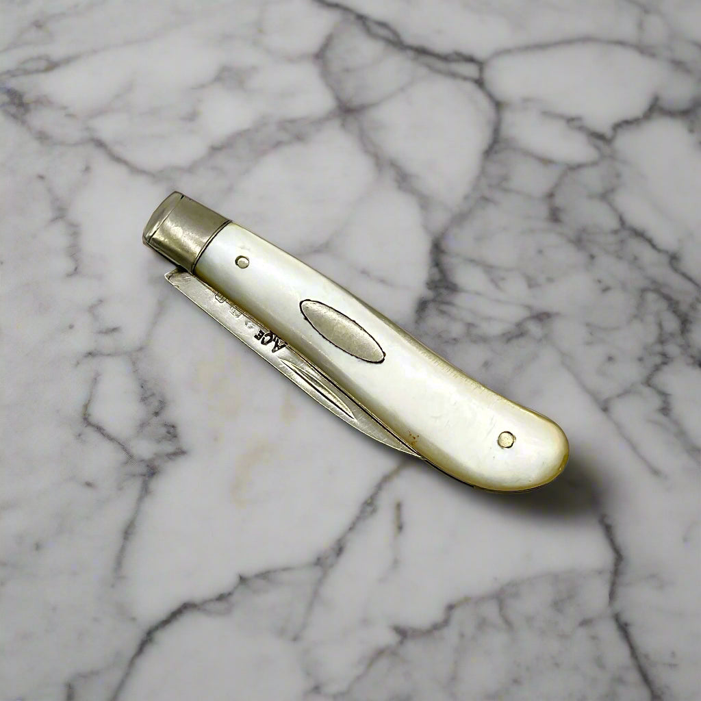 Silver bladed fruit knife with a mother of Pearl handle on a marble workbench  with the blade folded away