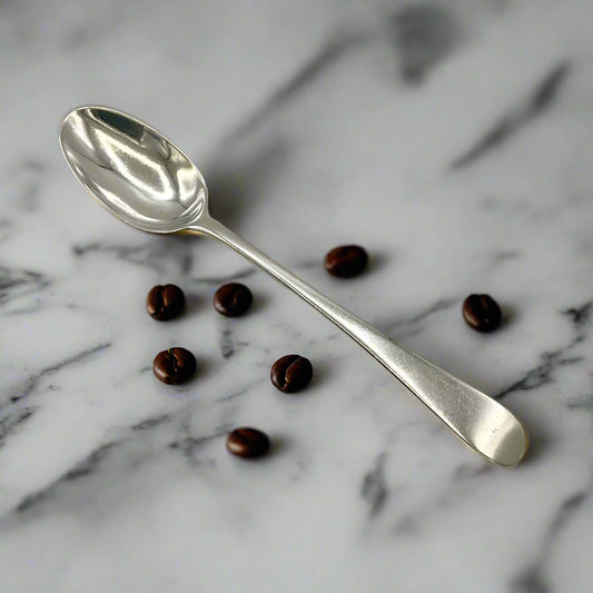 Silver coffee spoon on a marble workbench with a few coffee spoons
