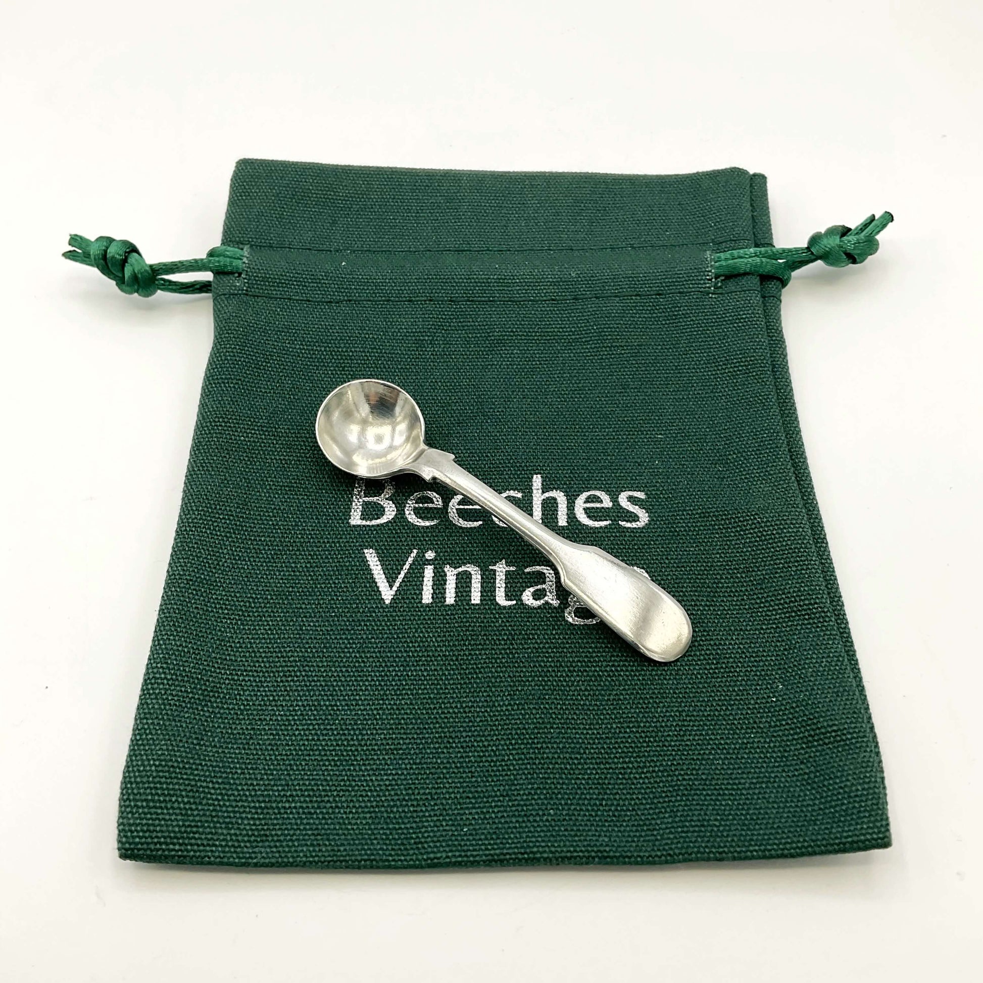 Antique silver salt spoon on a green gift bag and white background 