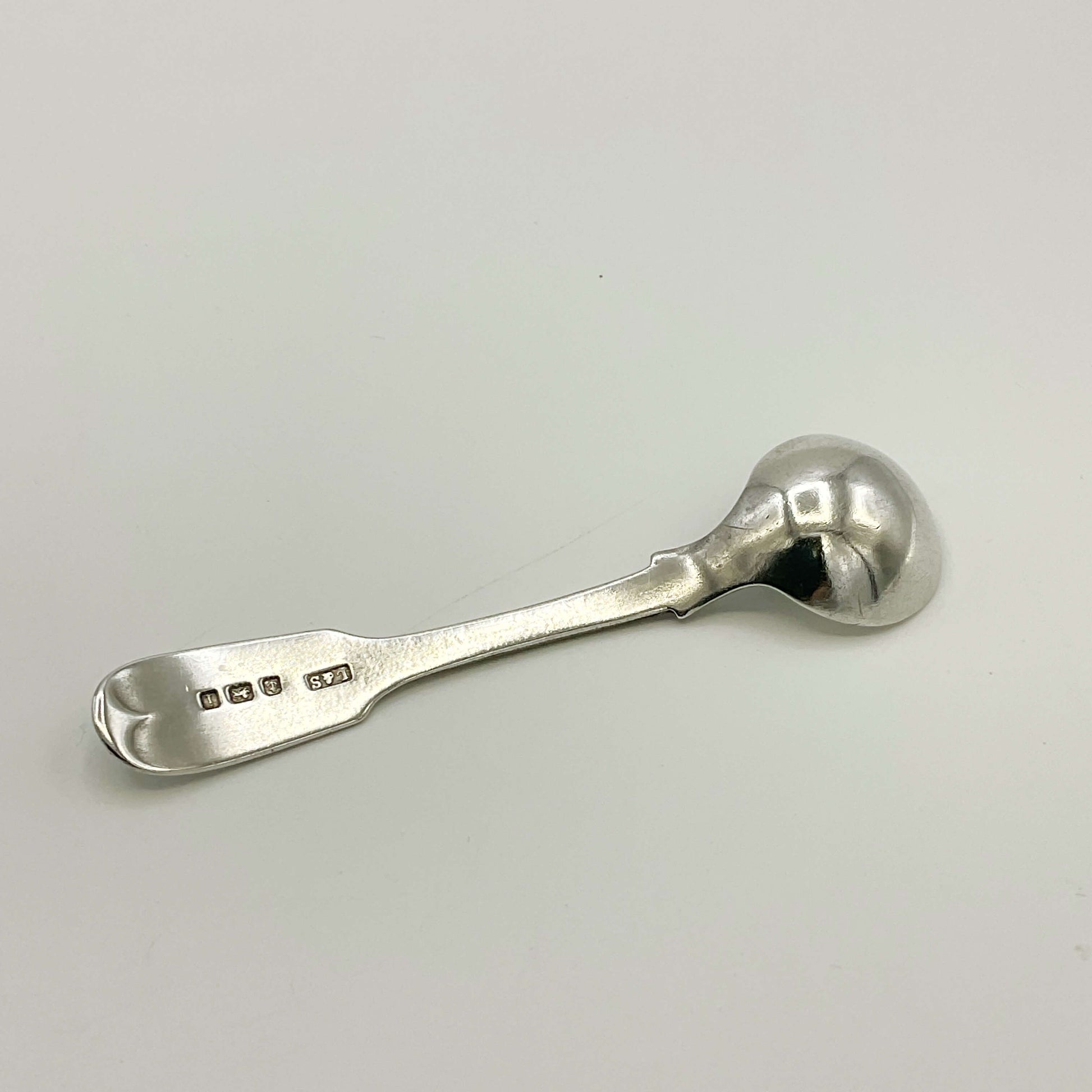 Back of Antique silver salt spoon on a white background 