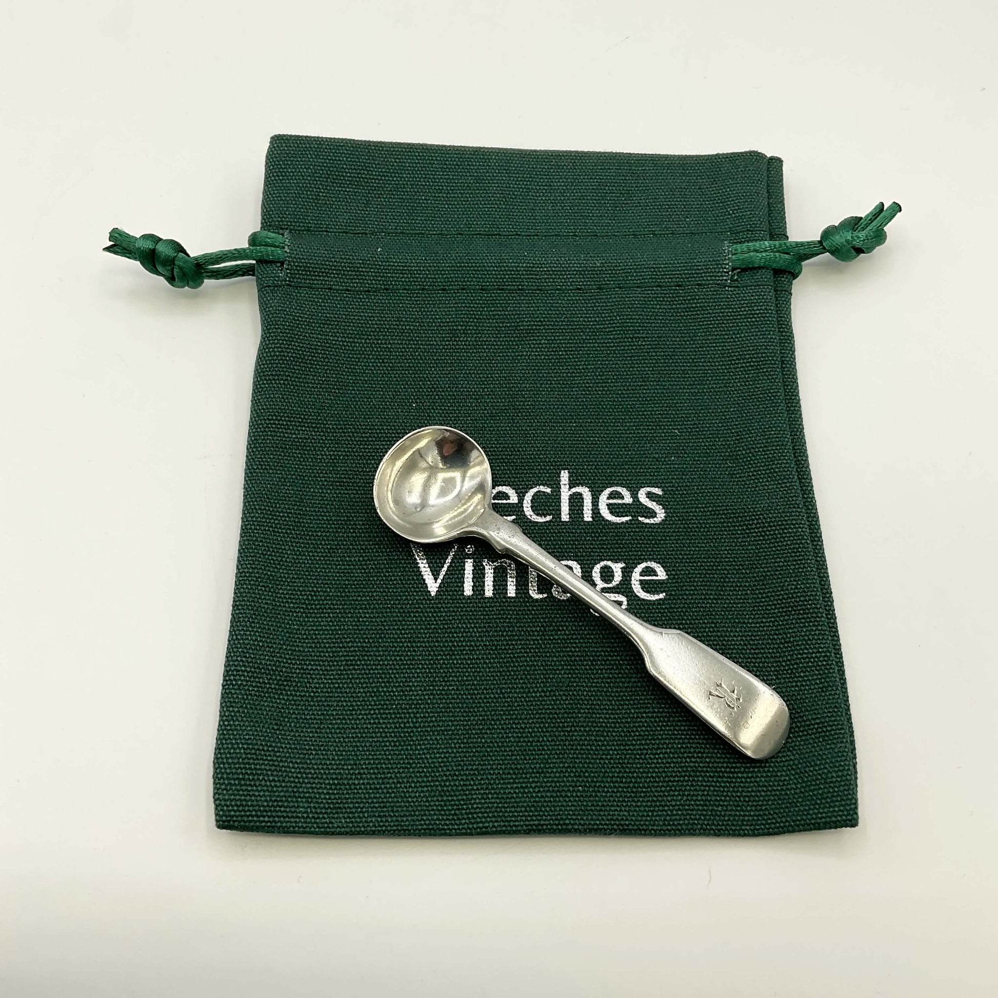 Antique silver salt spoon on a green gift bag and a white background 