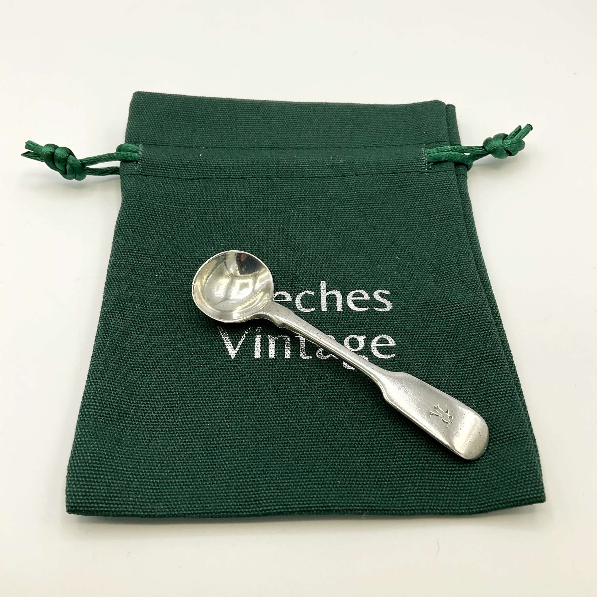 Antique silver salt spoon on a green gift bag and a white background 