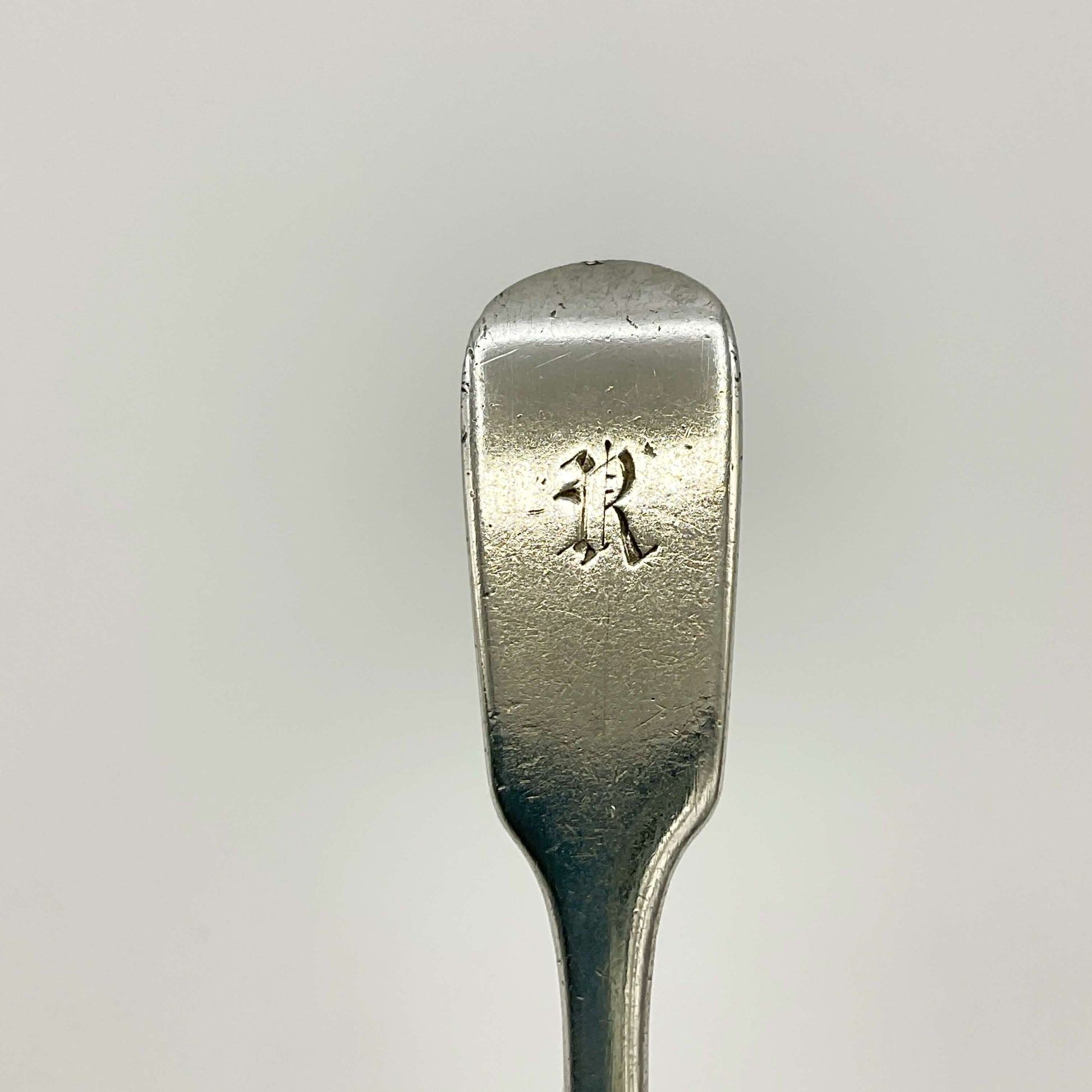 Gothic Letter R at the top of the siler spoon handle on a white background 