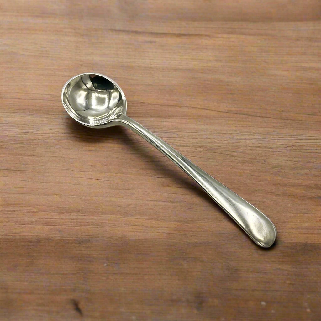 Small silver salt spoon on a wooden table