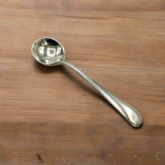 Small silver salt spoon on a wooden table