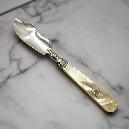 Antique silver and mother of pearl butter knife on a marble worktop
