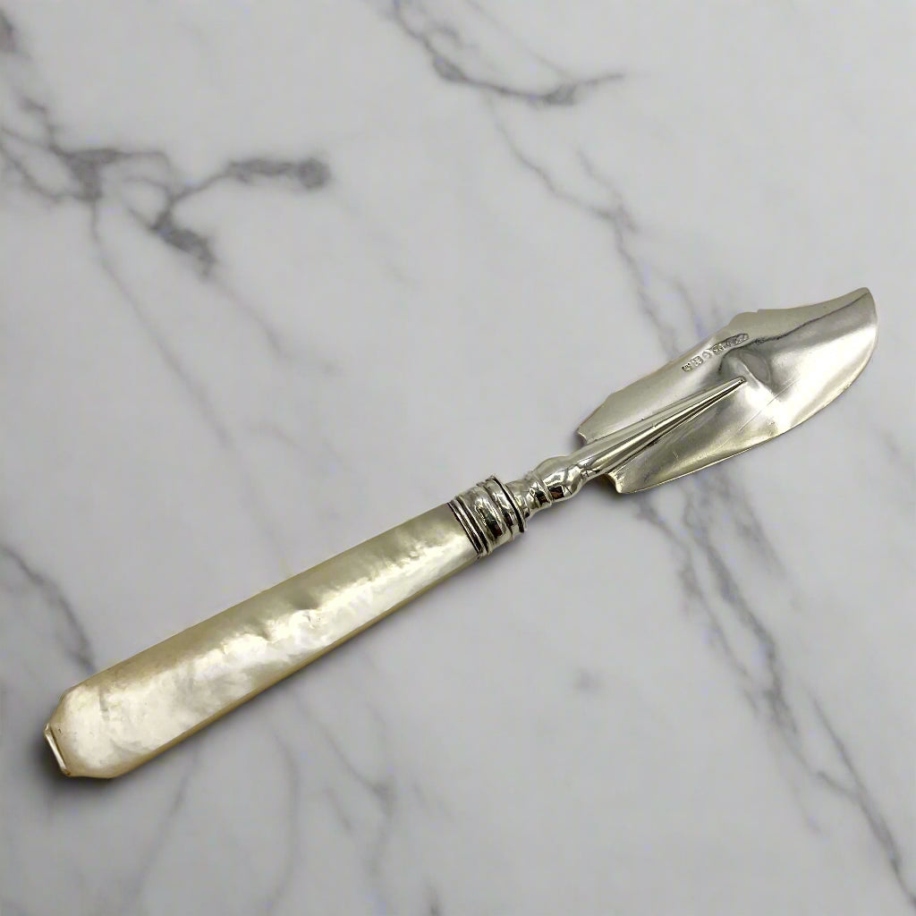 Antique silver and mother of pearl butter knife on a marble worktop