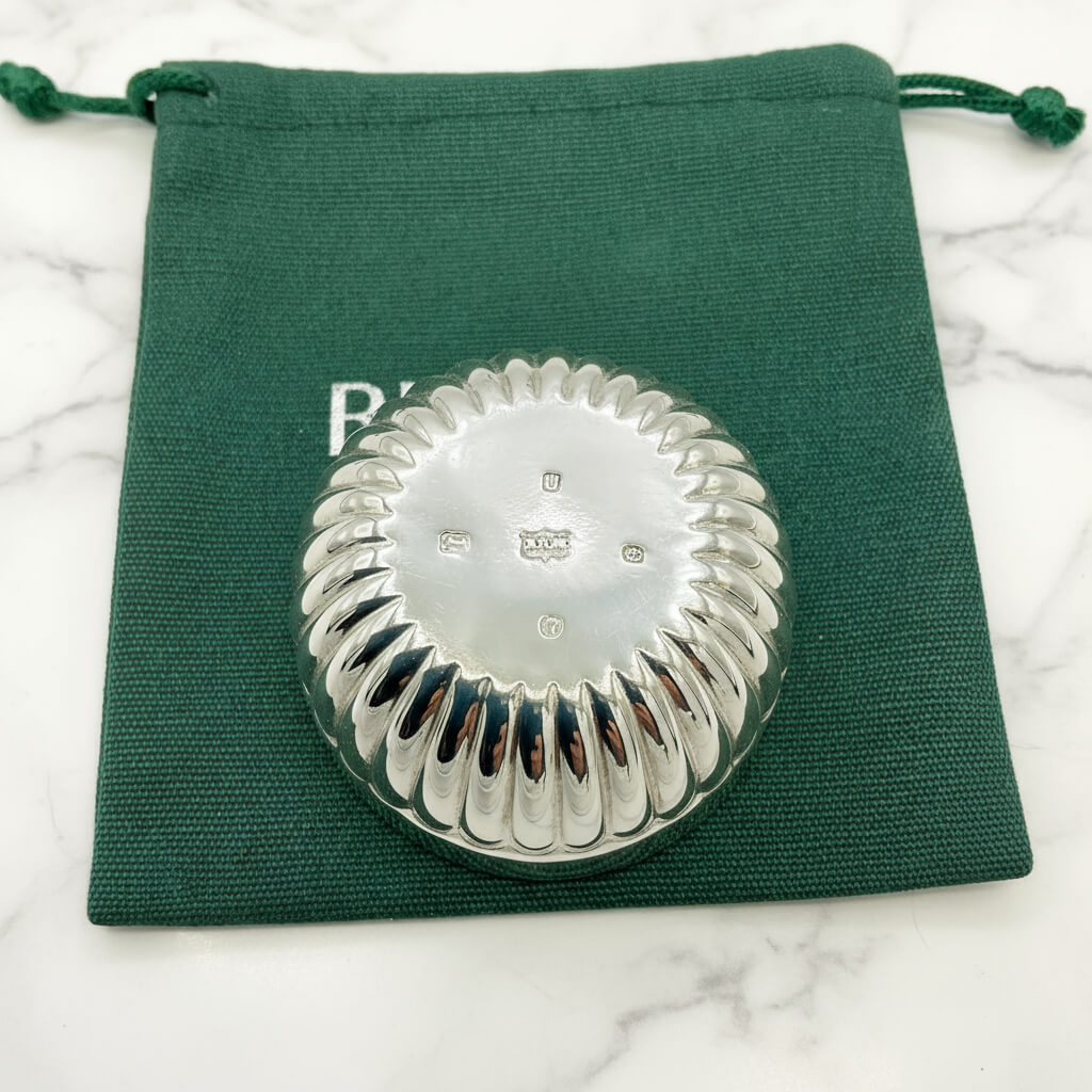 Silver ring with textured design on green fabric background