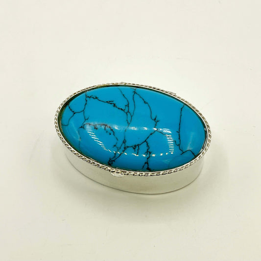 Turquoise and silver pill box on a white background 