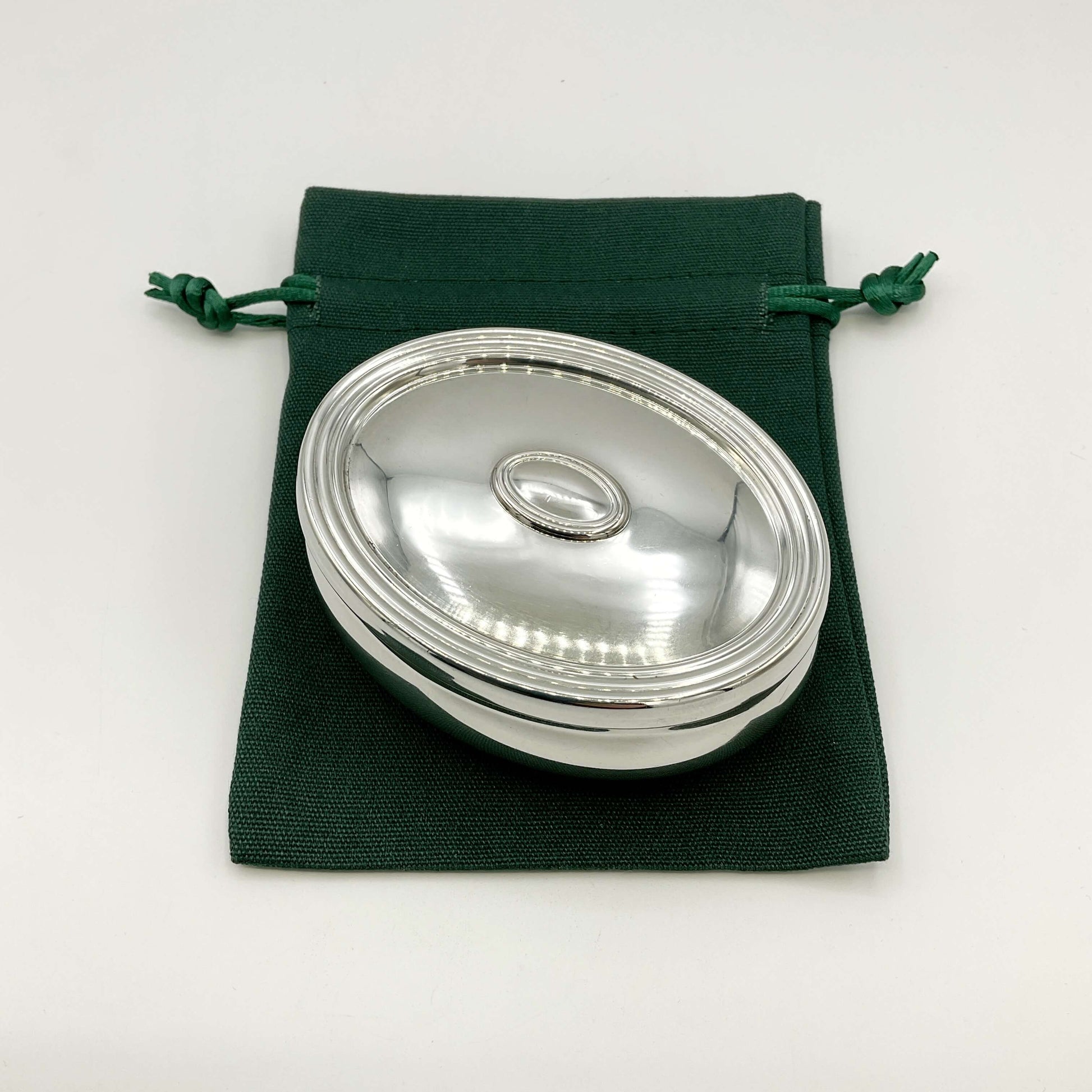 Silver trinket box on a green gift bag and white background 
