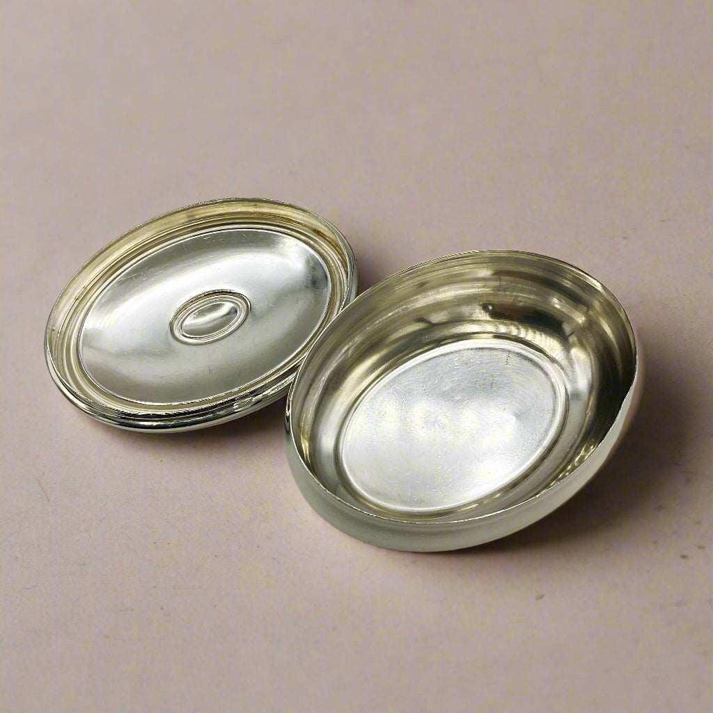 Interior of silver trinket box and lid on a light wood surface