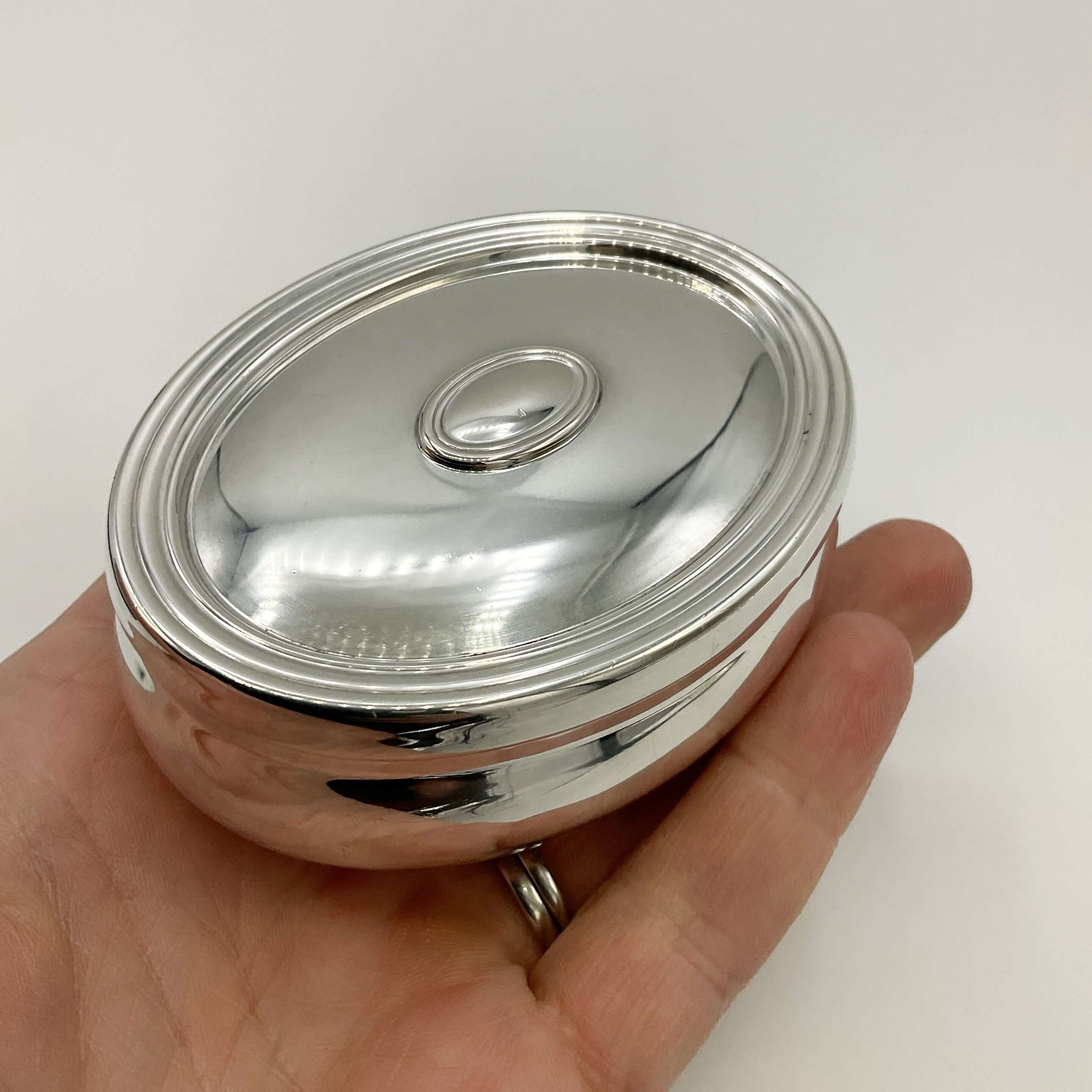 Silver trinket box in a hand with a white background 