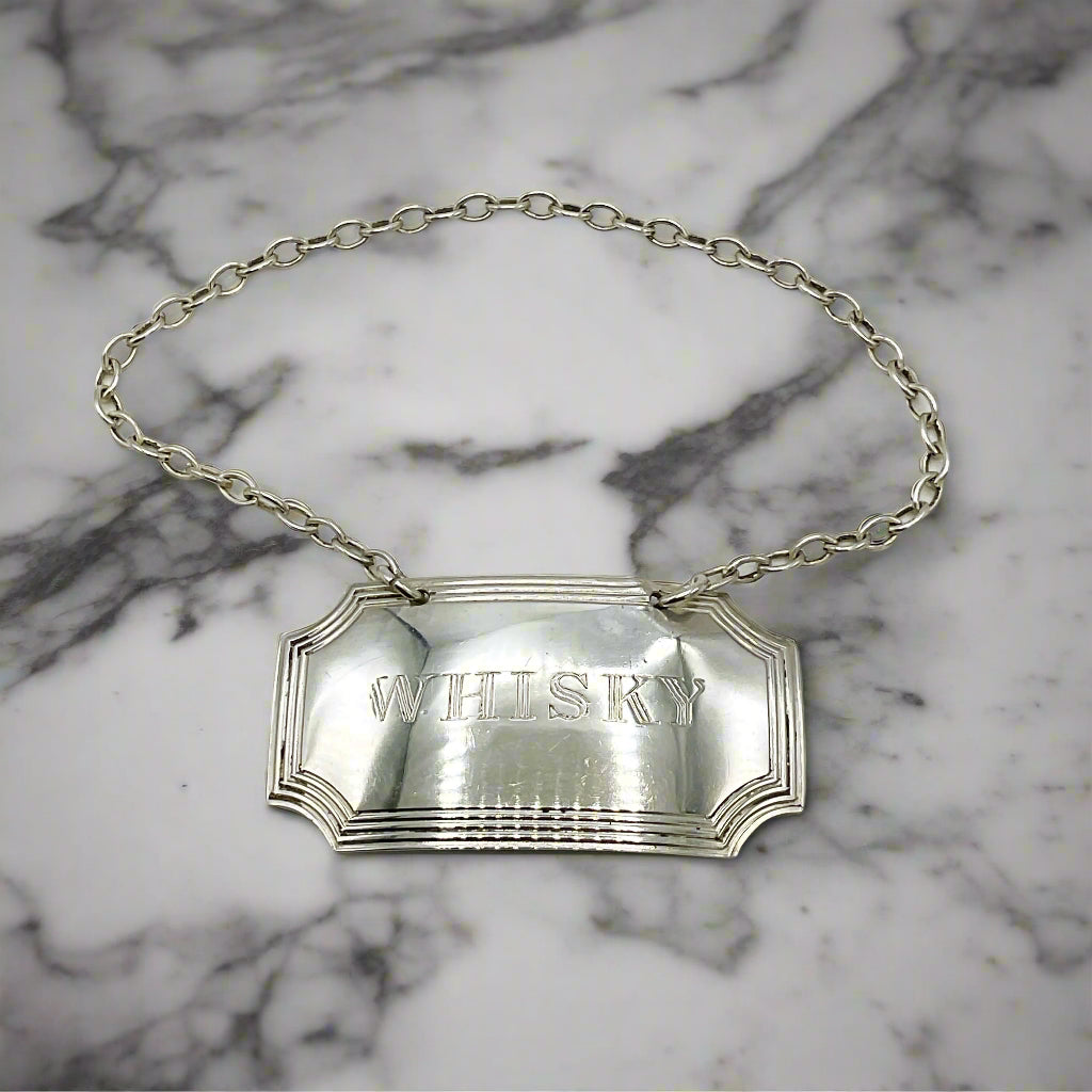 Silver whisky decanter label on a marble worktop