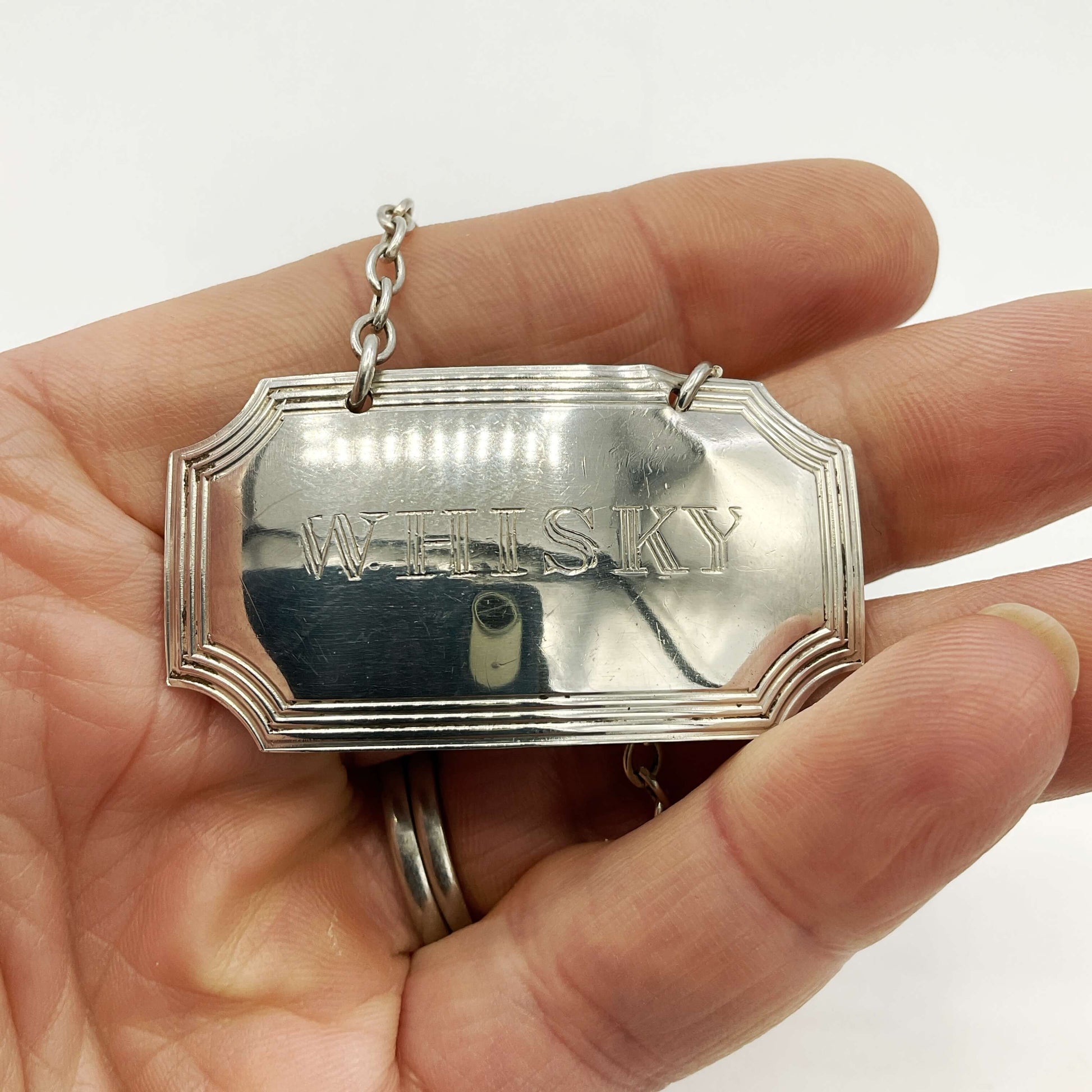 Silver Whisky decanter label in front of on a white background 