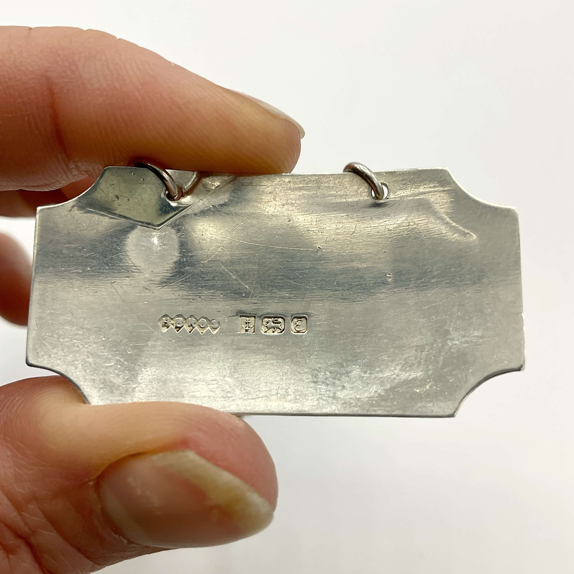 Back of silver decanter label showing the maker’s mark and hallmarks