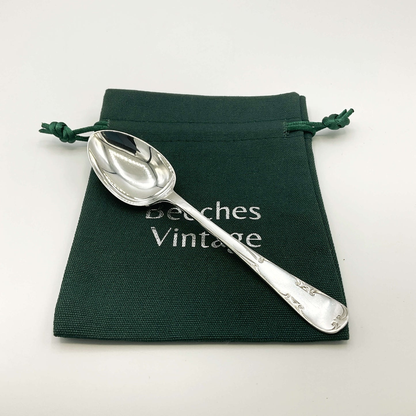 Silver teaspoon on a green gift bag and white background 