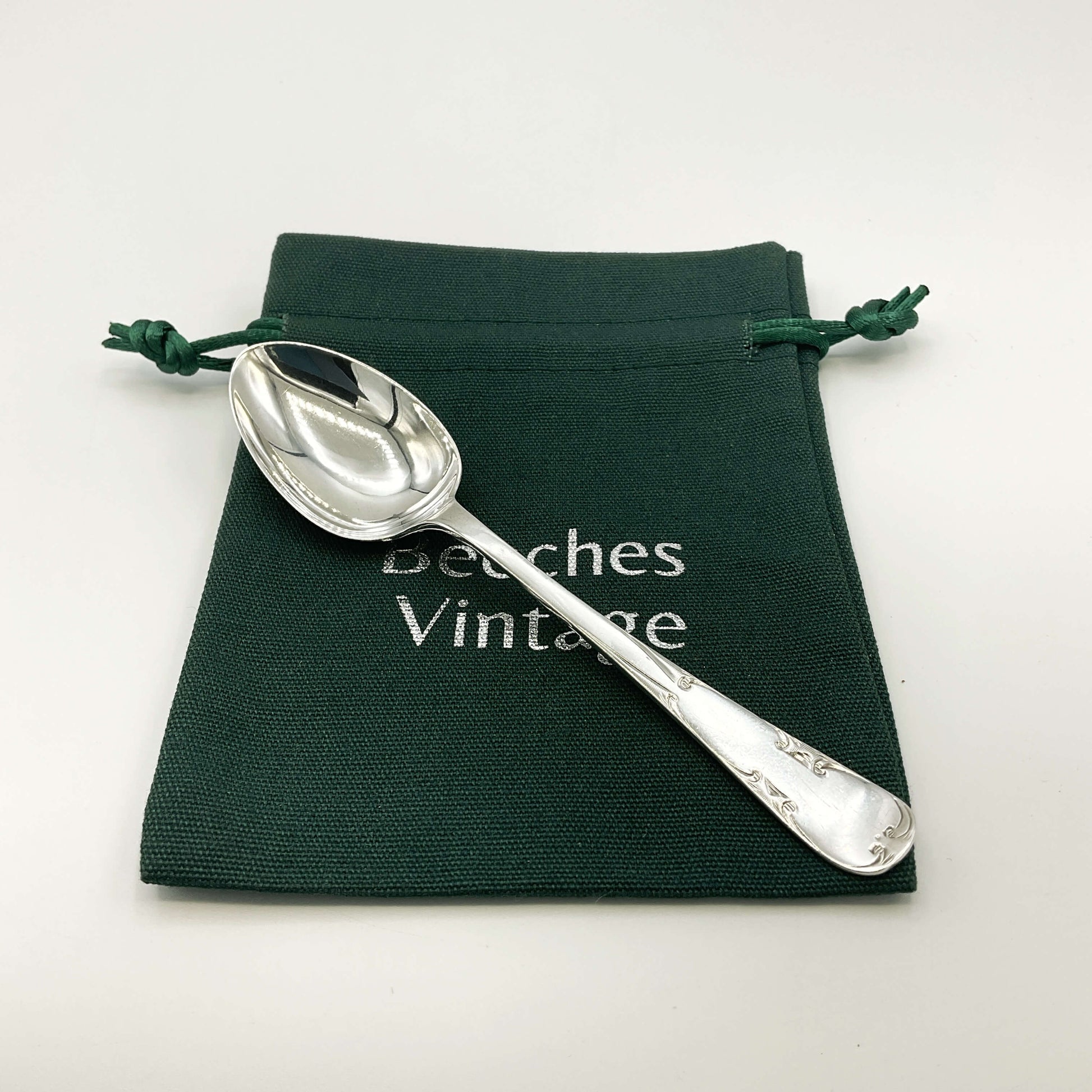 Silver teaspoon on a green gift bag and white background 