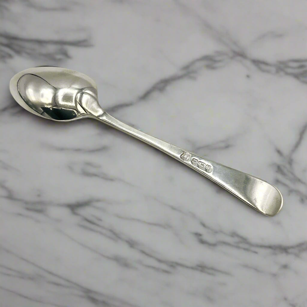 Back of antique silver teaspoon on a marble worktop 