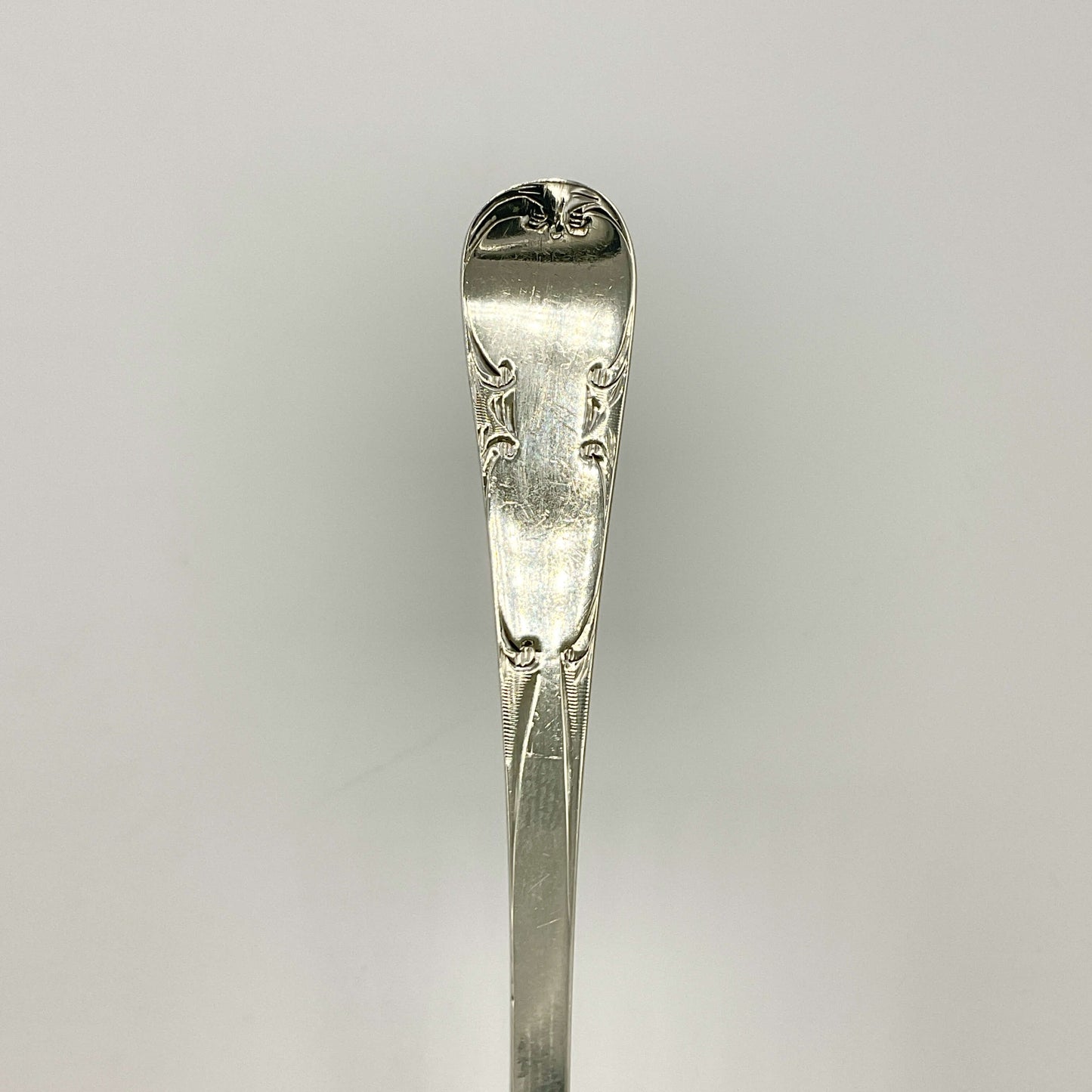 Antique silver teaspoon handle with a white background 