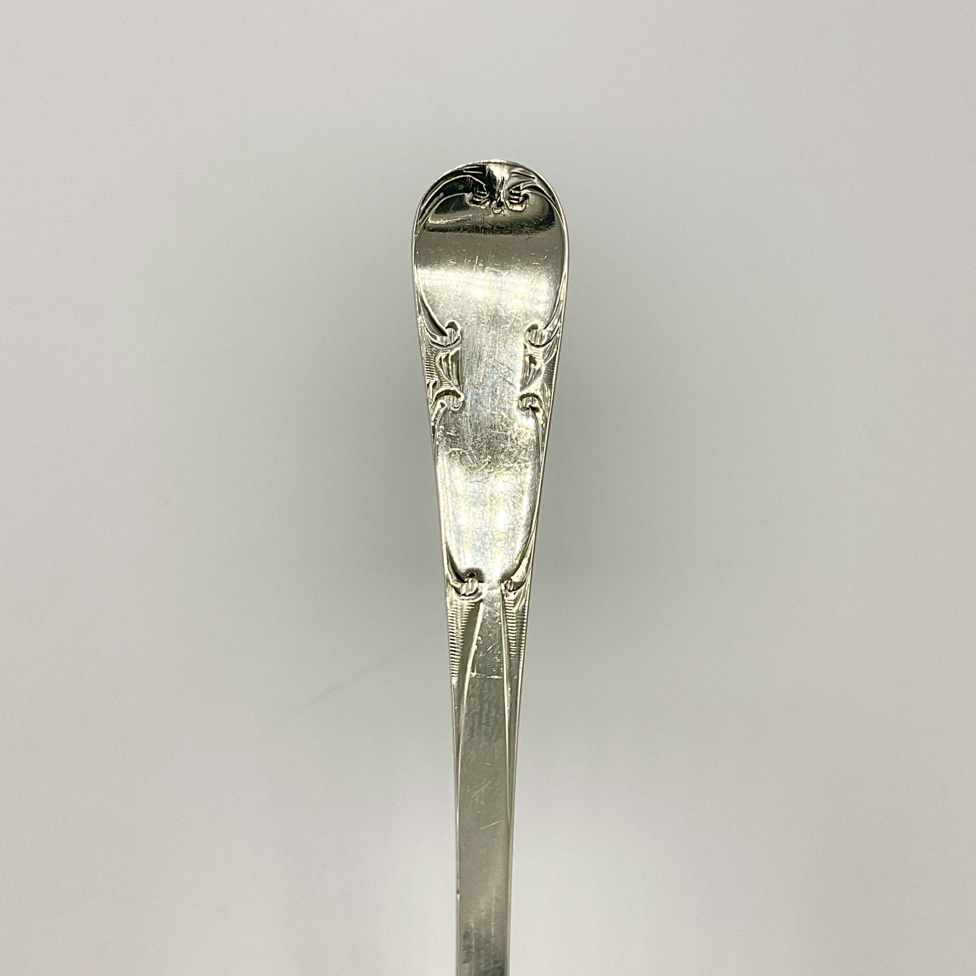 Antique silver teaspoon handle with a white background 