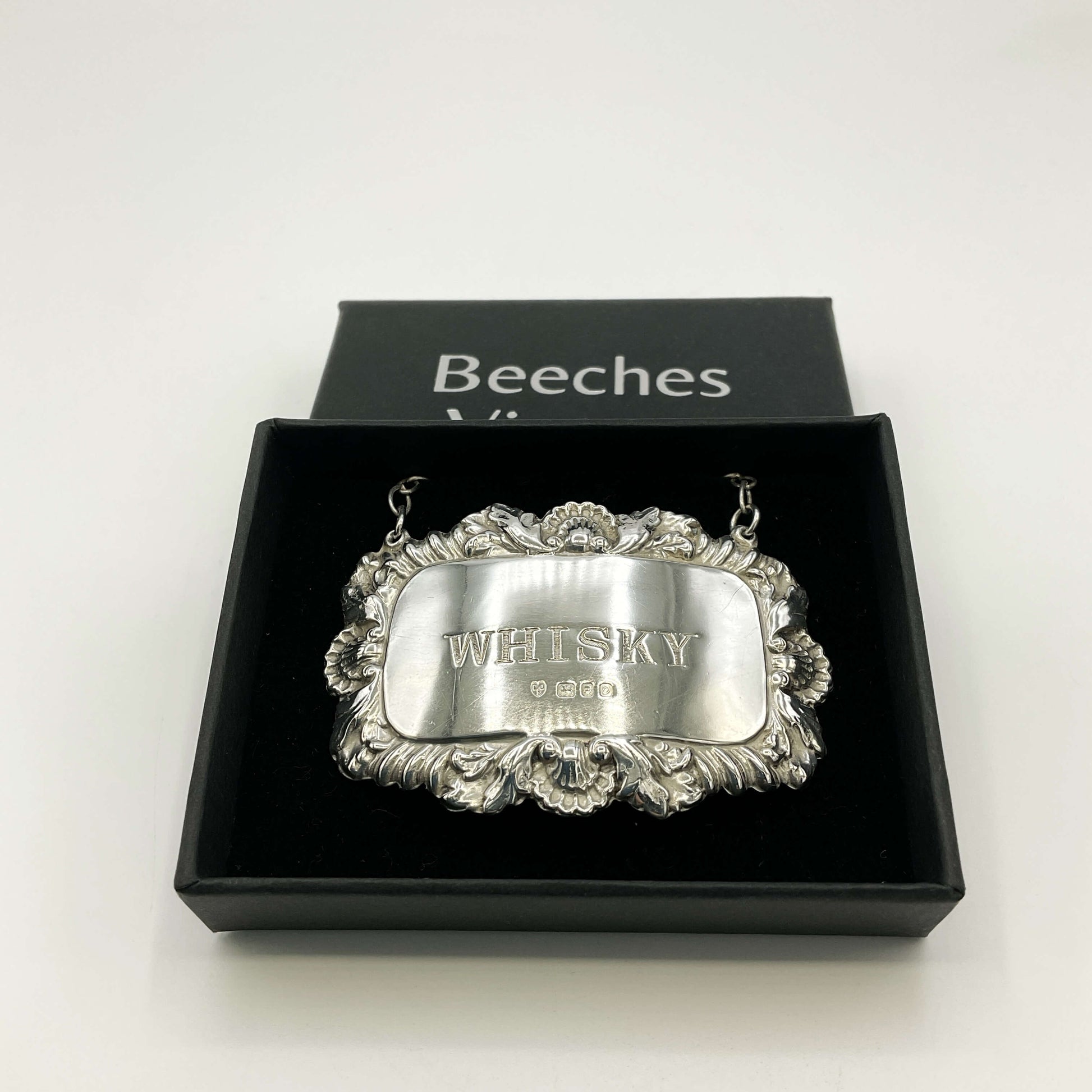 Silver whisky decanter label in a black presentation box and a white background 