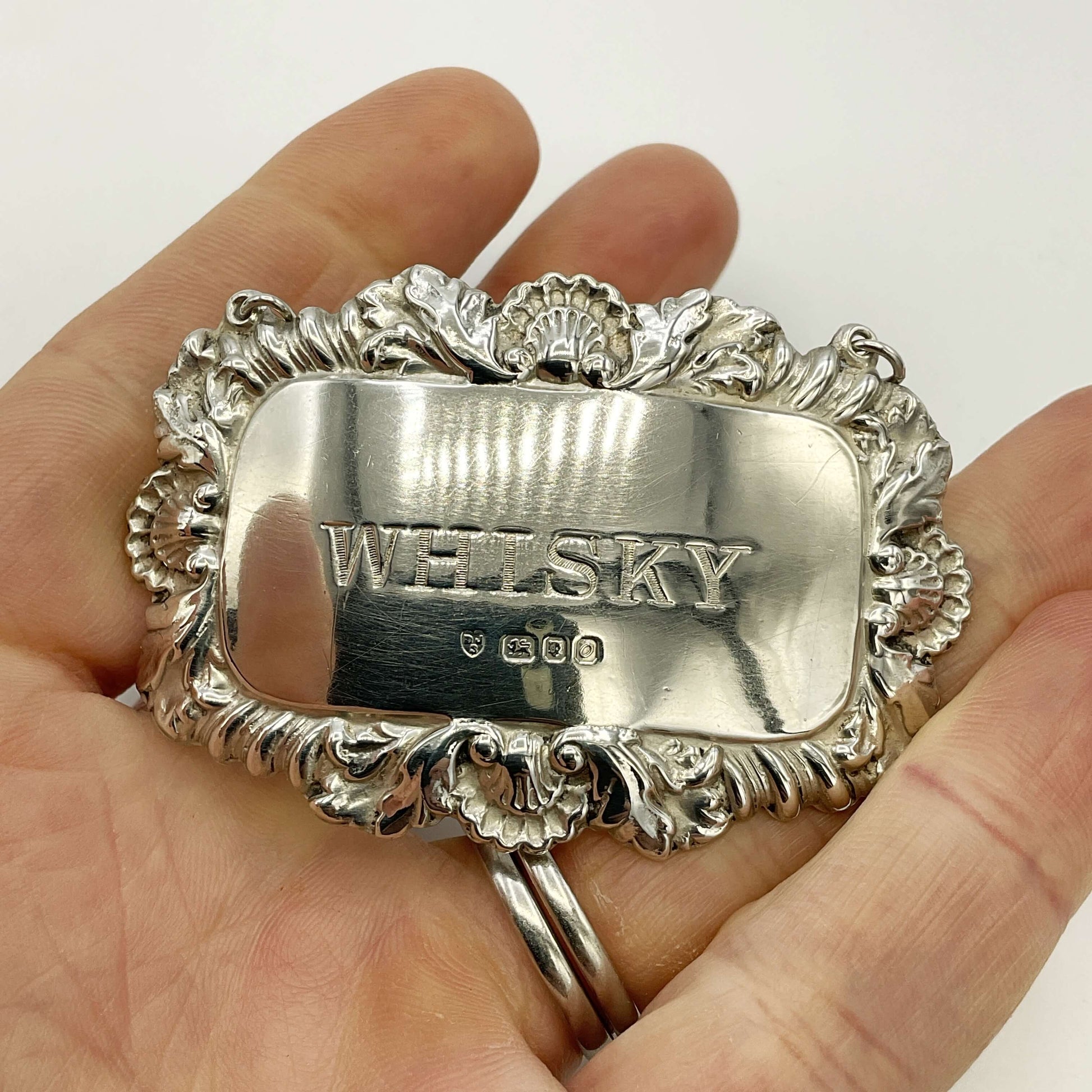 Whisky decanter label held in a hand with a white background 