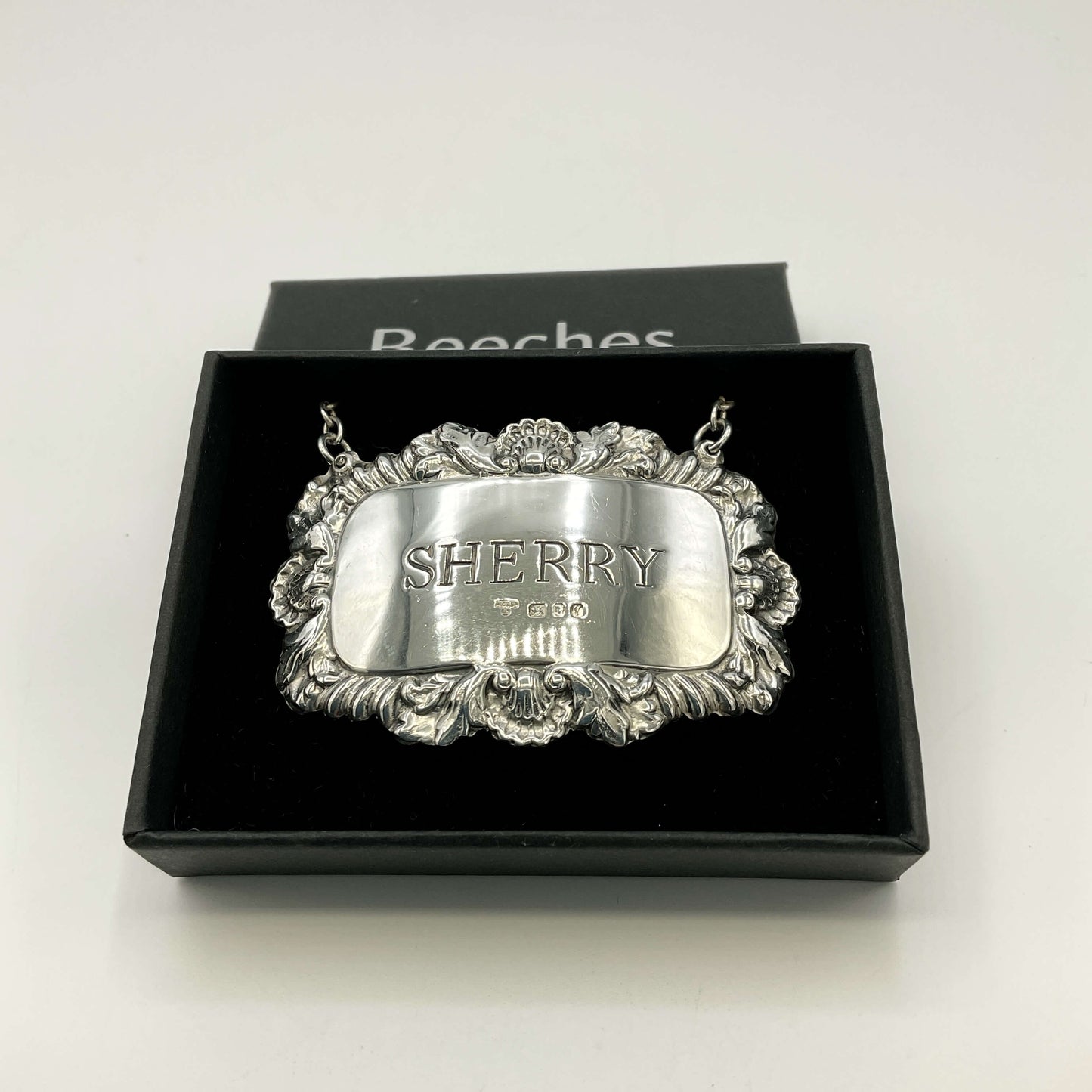 Silver Sherry decanter label in  a black presentation box with a white background 