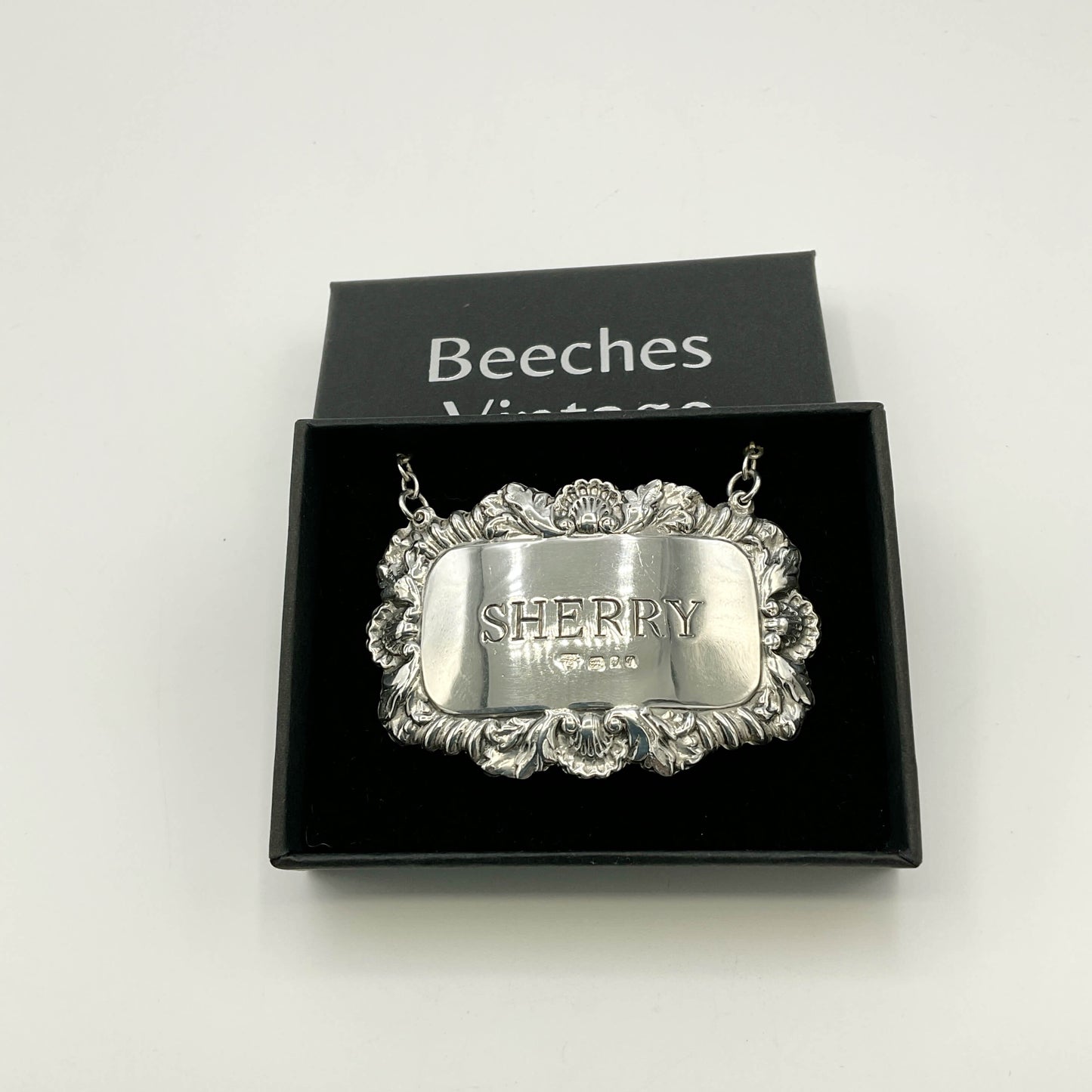 Silver Sherry decanter label in  a black presentation box with a white background 