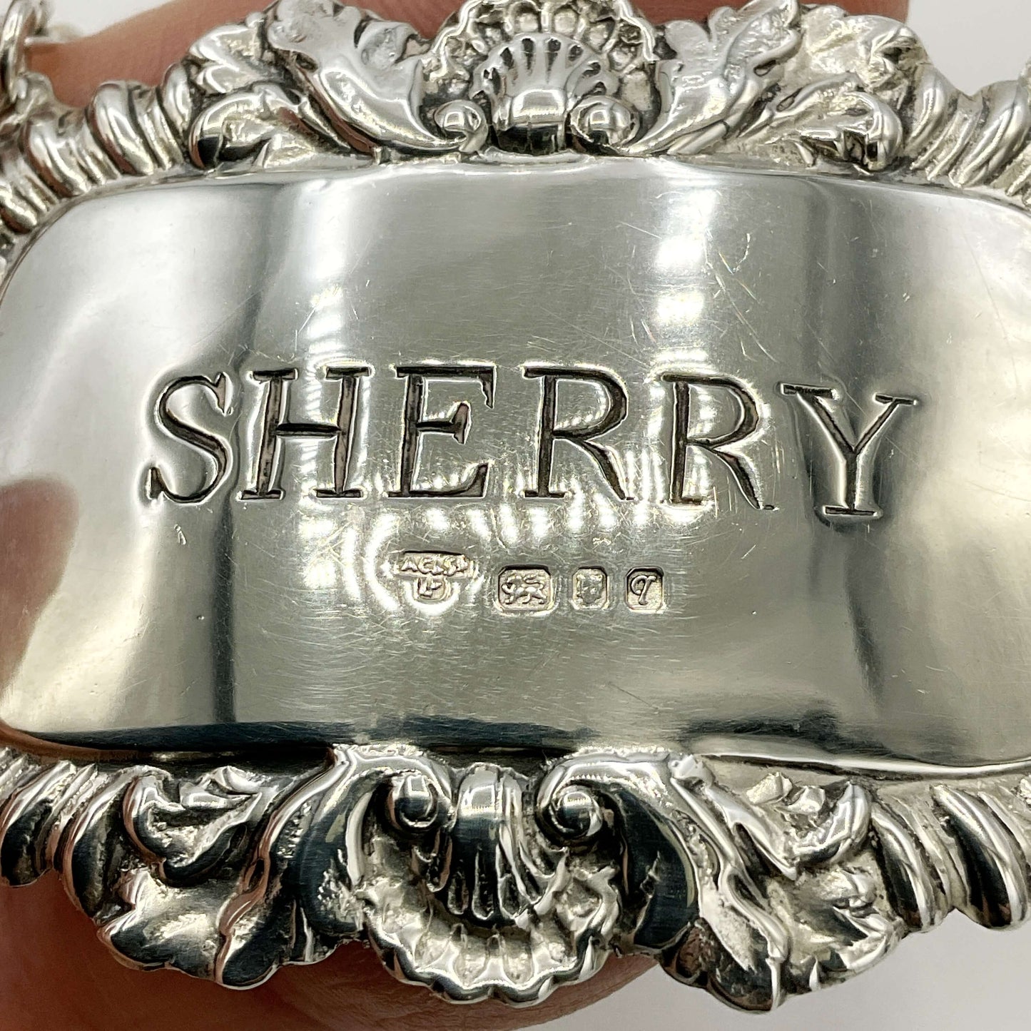 Close up of silver Sherry decanter label showing the maker’s mark and hallmarks 