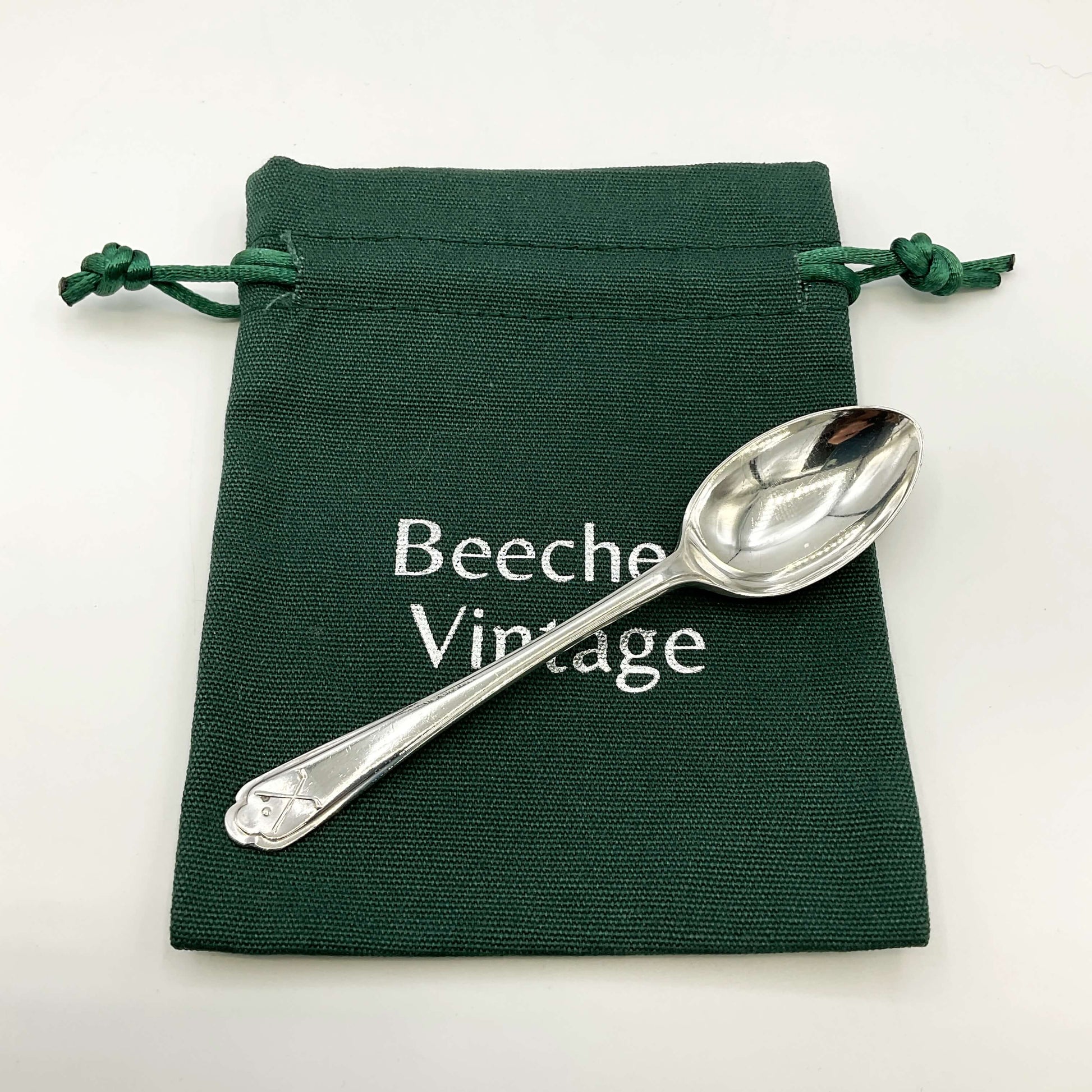Silver coffee spoon on a green gift bag and white background 
