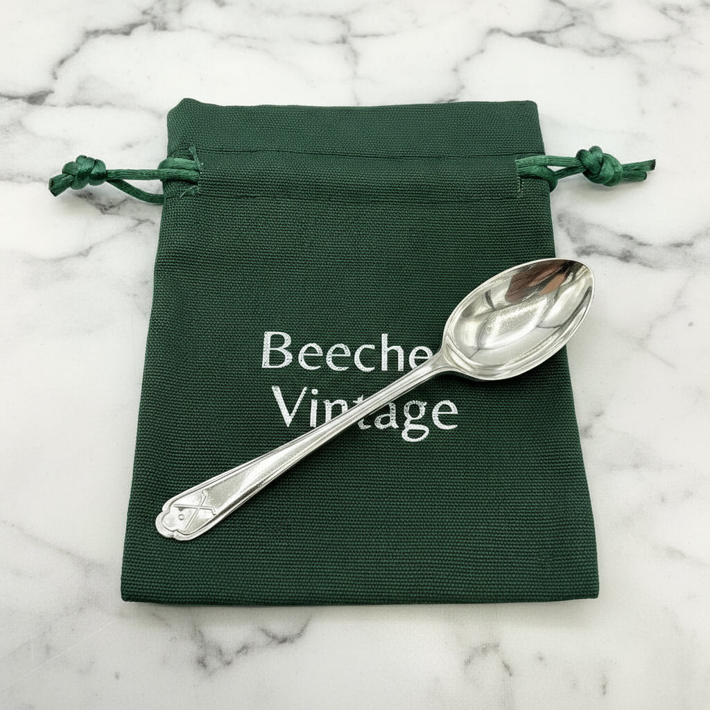 Silver coffee spoon on a green gift bag and marble background 