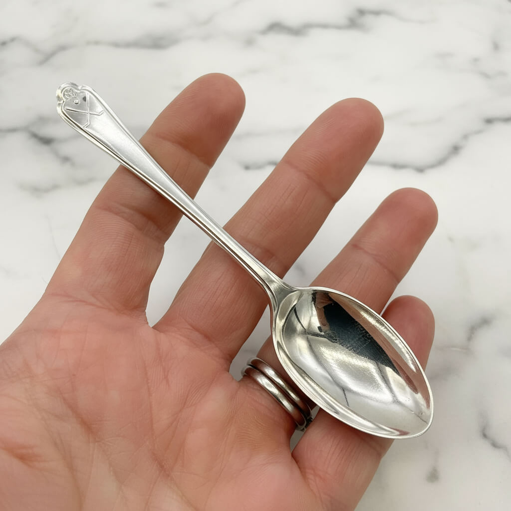 Silver coffee spoon held in a hand with a marble background 